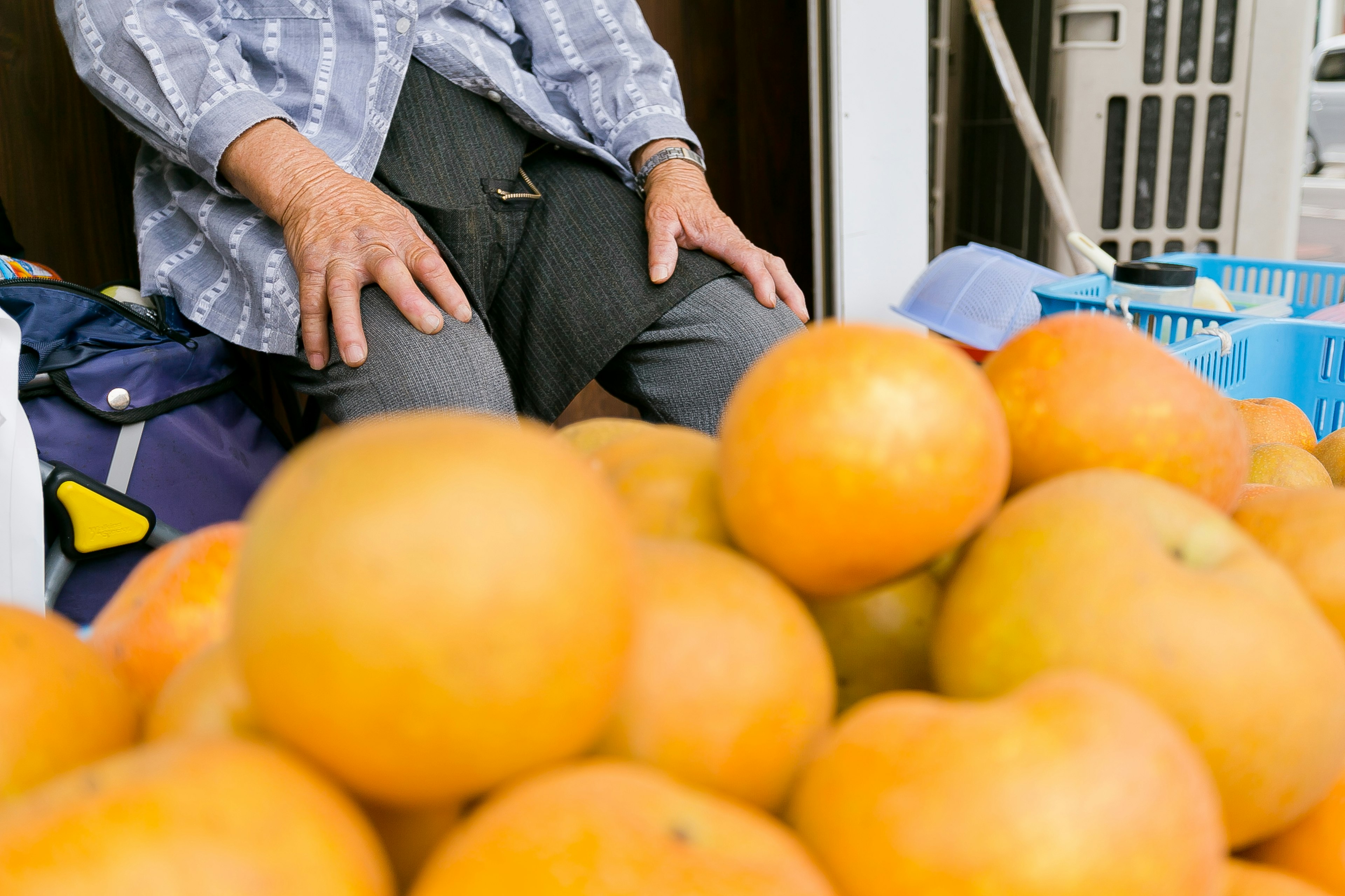 Une pile de fruits orange vif avec une personne assise en arrière-plan