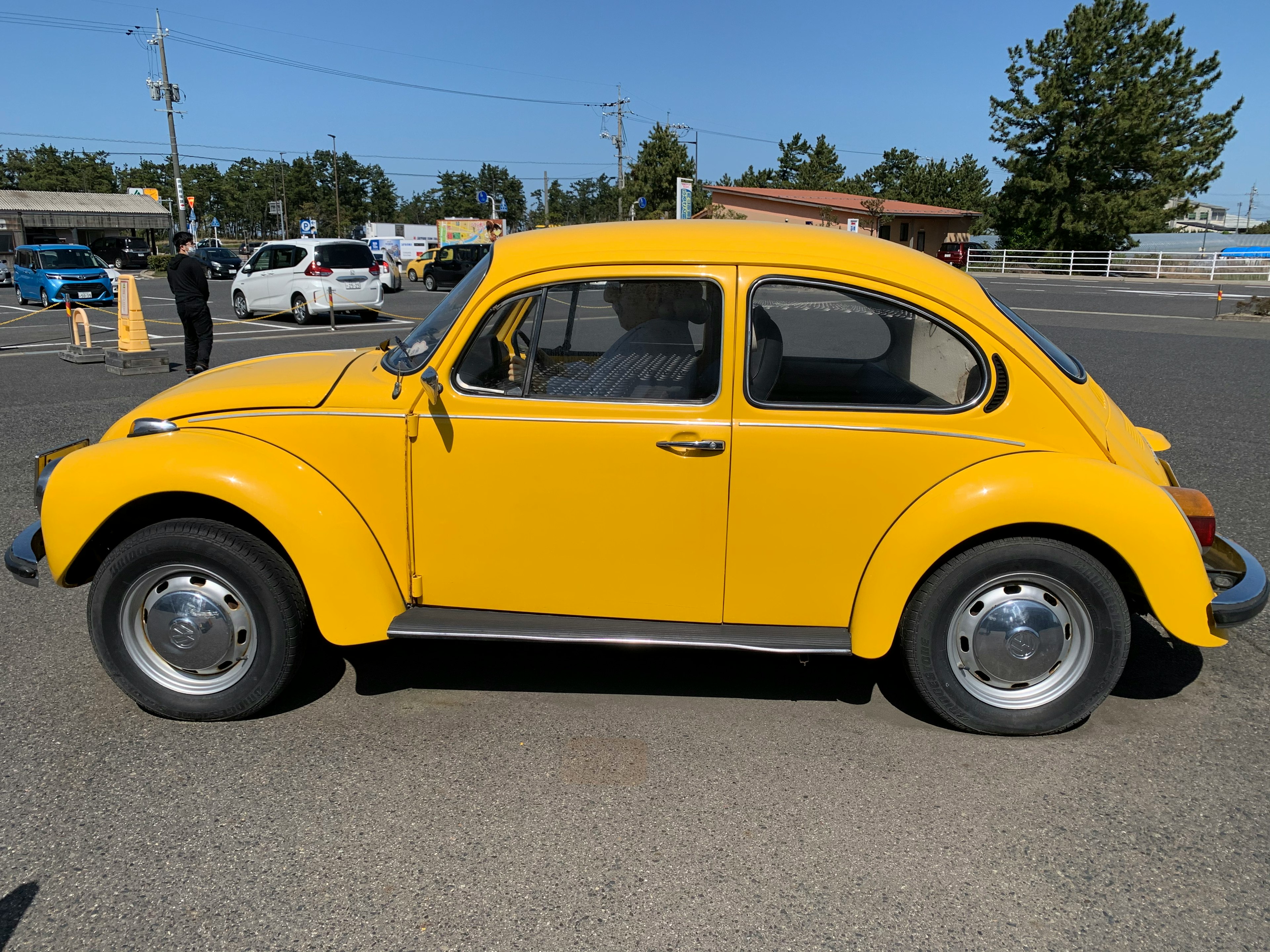 Vue latérale d'une voiture Beetle jaune sous un ciel bleu clair