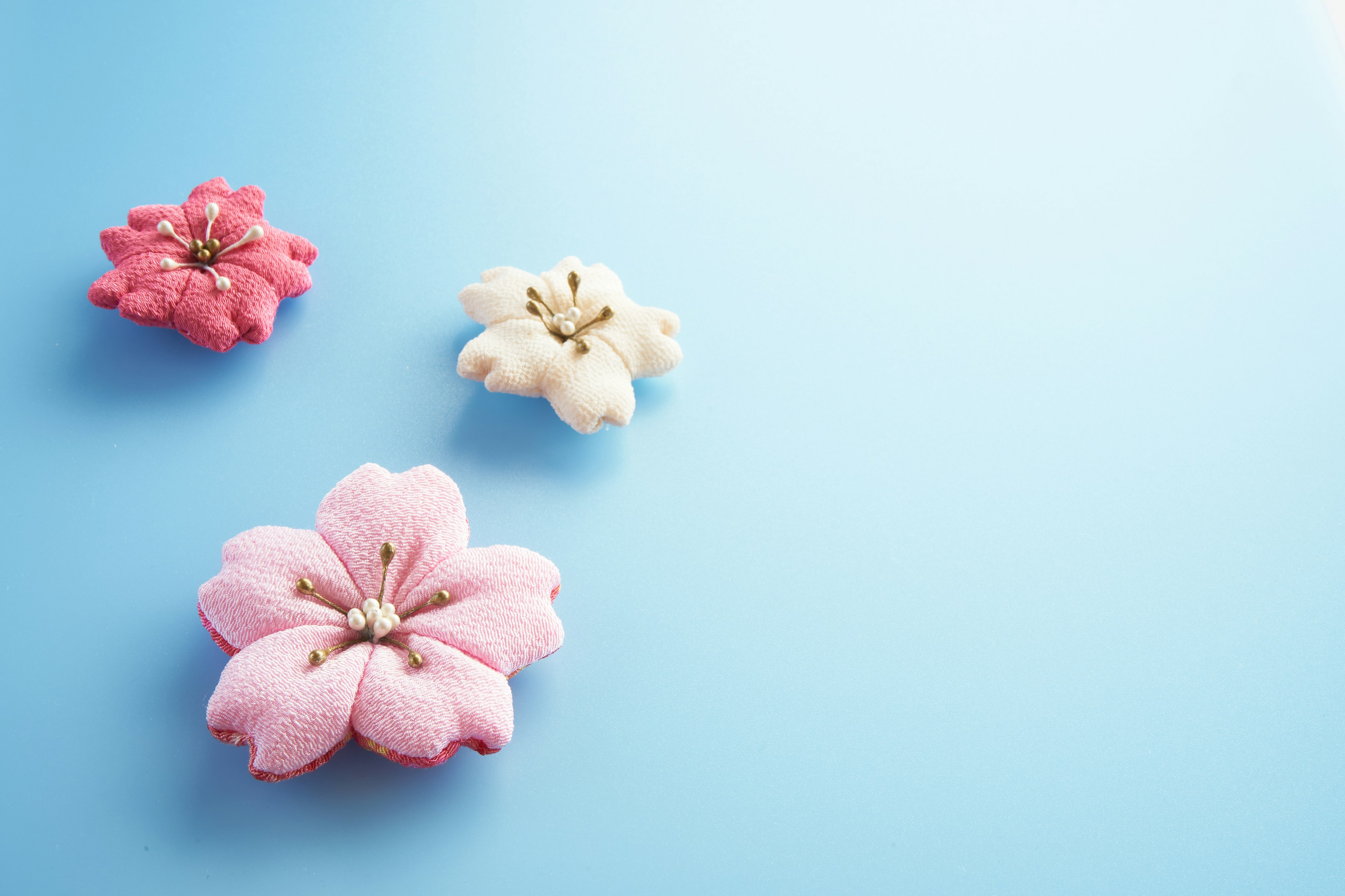 Drei blütenförmige Macarons in Rosa und Weiß auf blauem Hintergrund