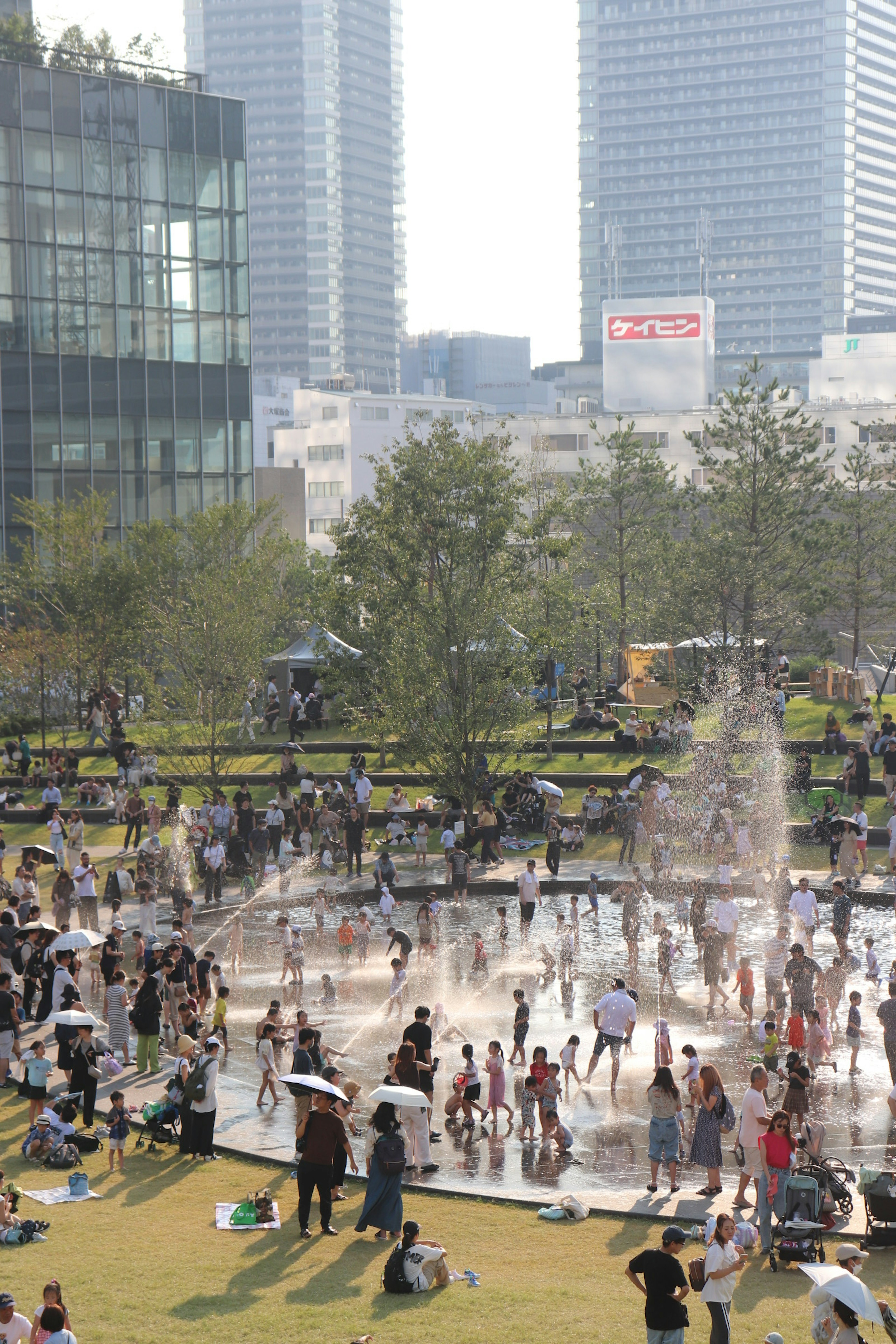 人々が噴水の周りで遊んでいる都市公園の風景