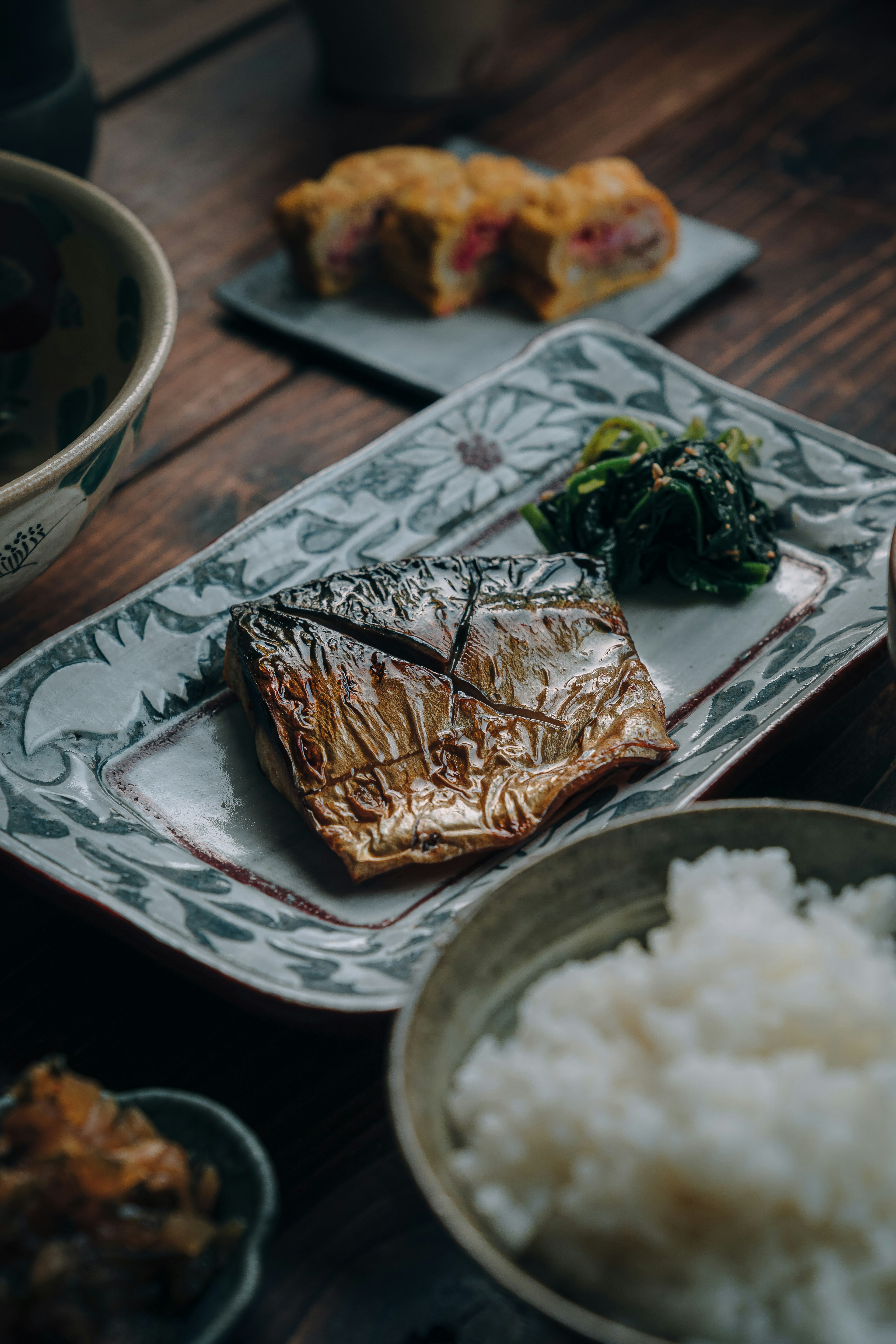 A beautifully arranged plate featuring grilled fish accompanied by rice and side dishes