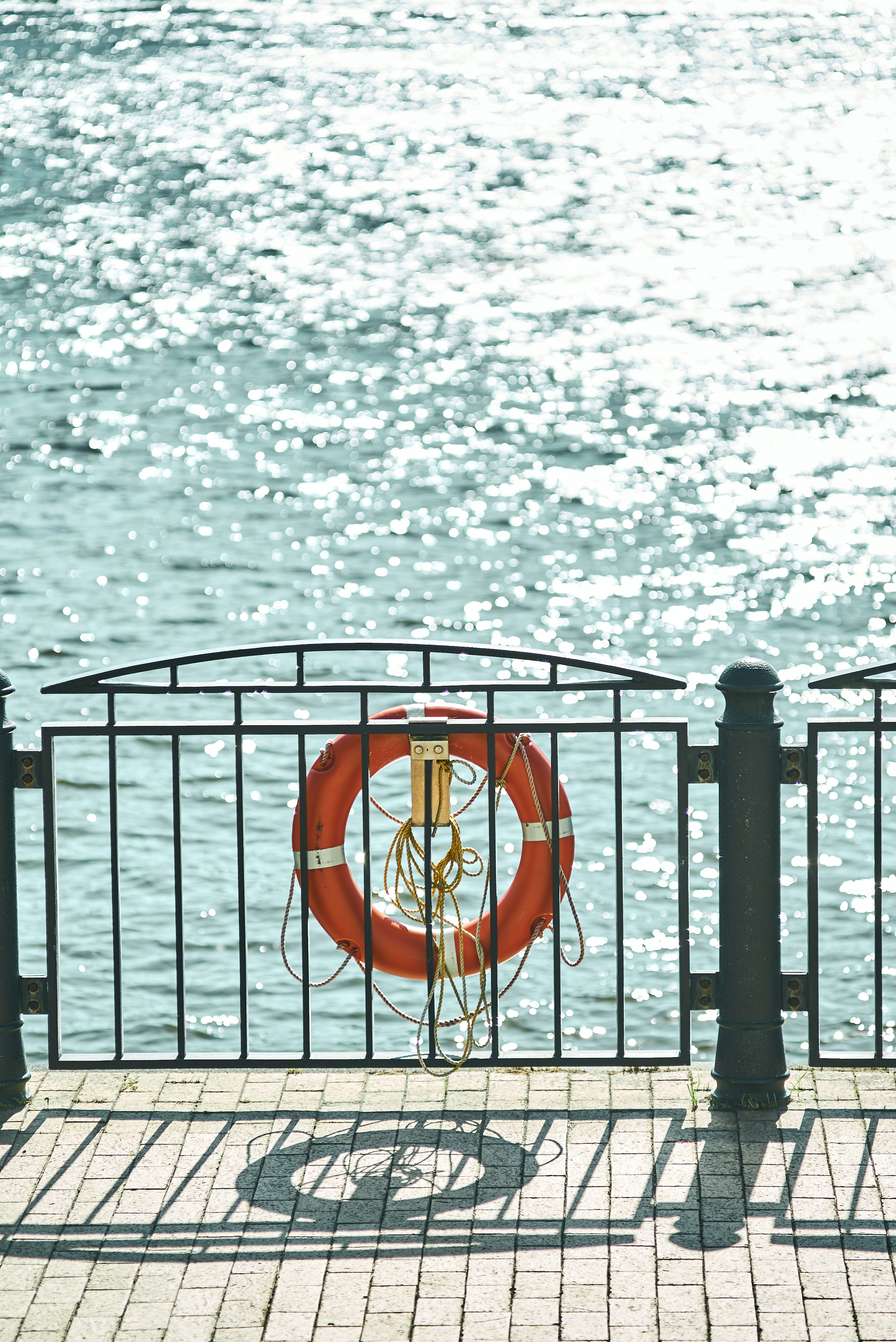 Szene in der Nähe eines Zauns mit einem roten Rettungsring und schimmerndem Wasser