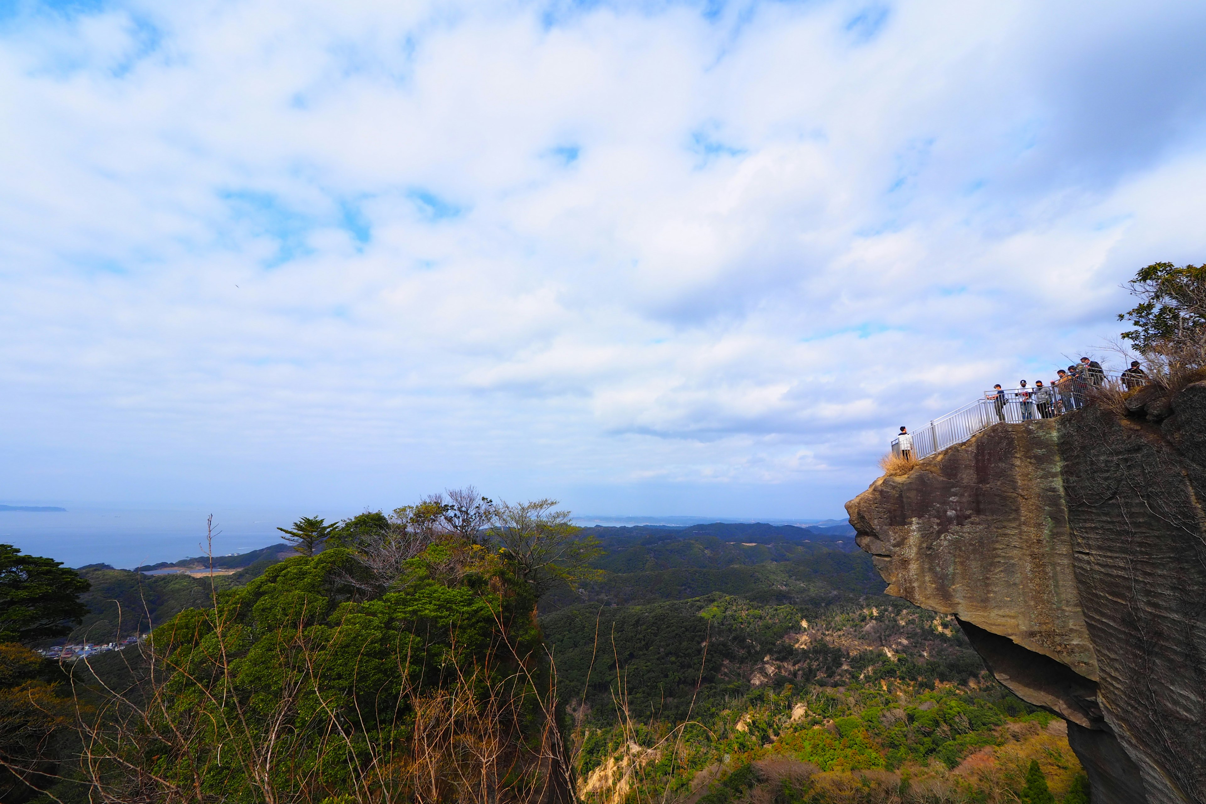 Scenic view of cliffs and lush greenery under a vast sky