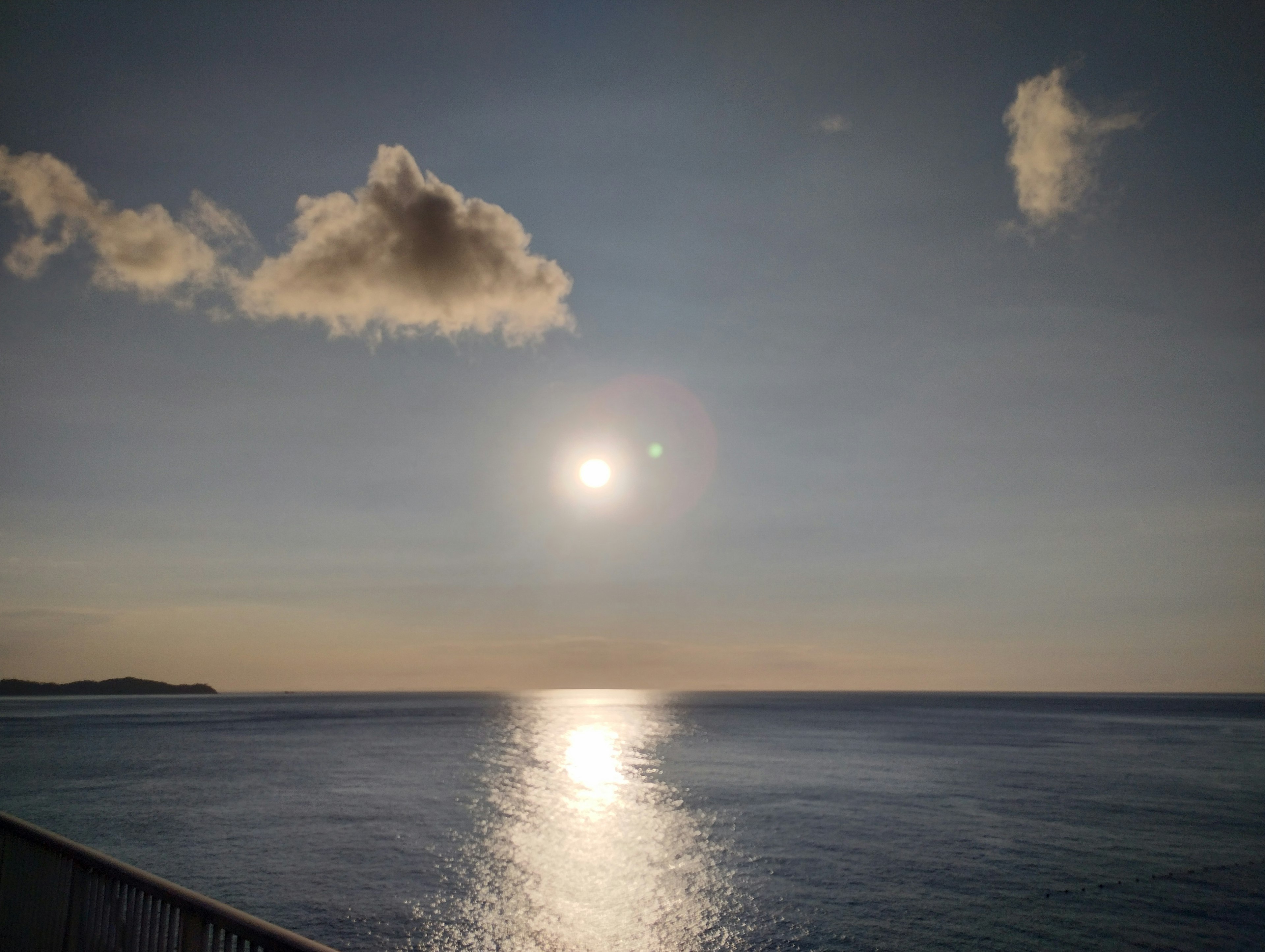 Ruhiges Meer mit hellem Sonnenlicht und Wolken