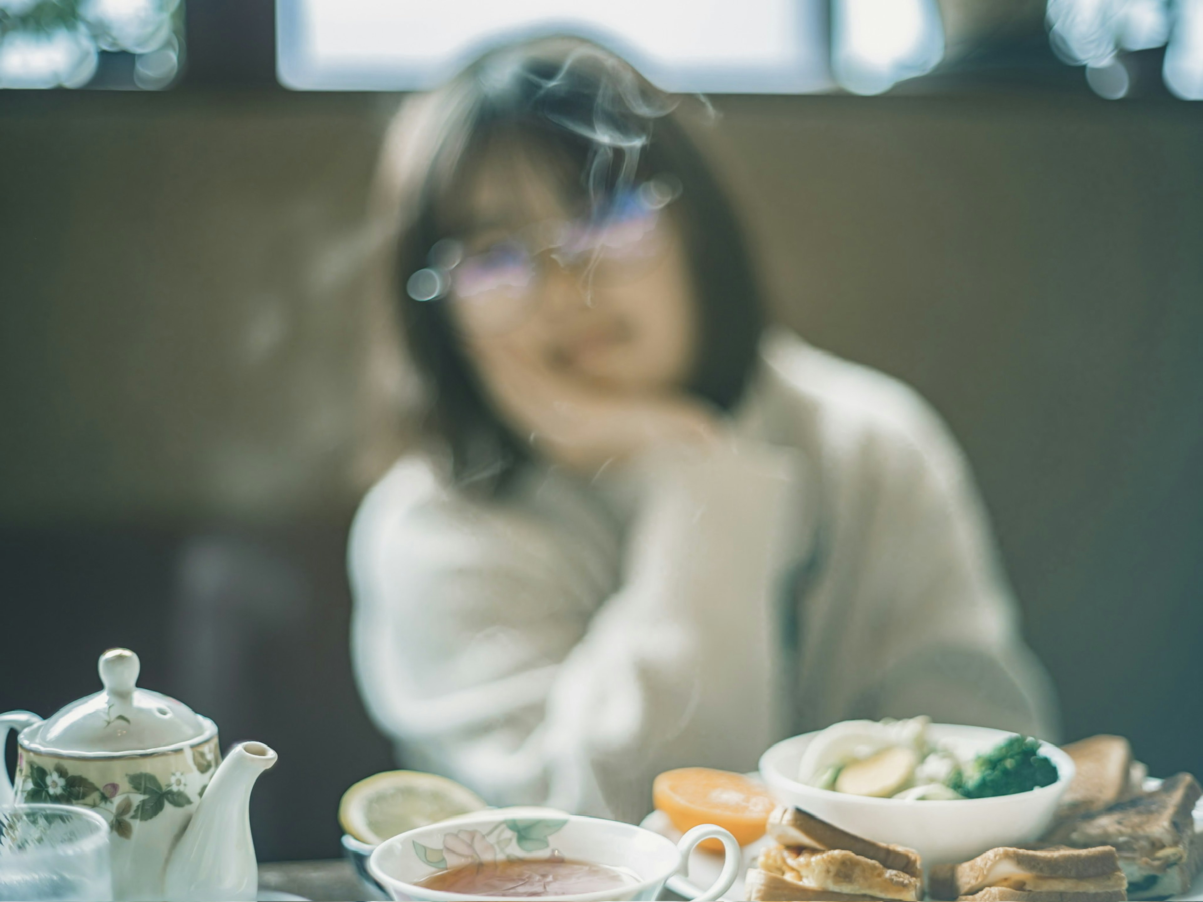 A woman deep in thought with tea and food on the table