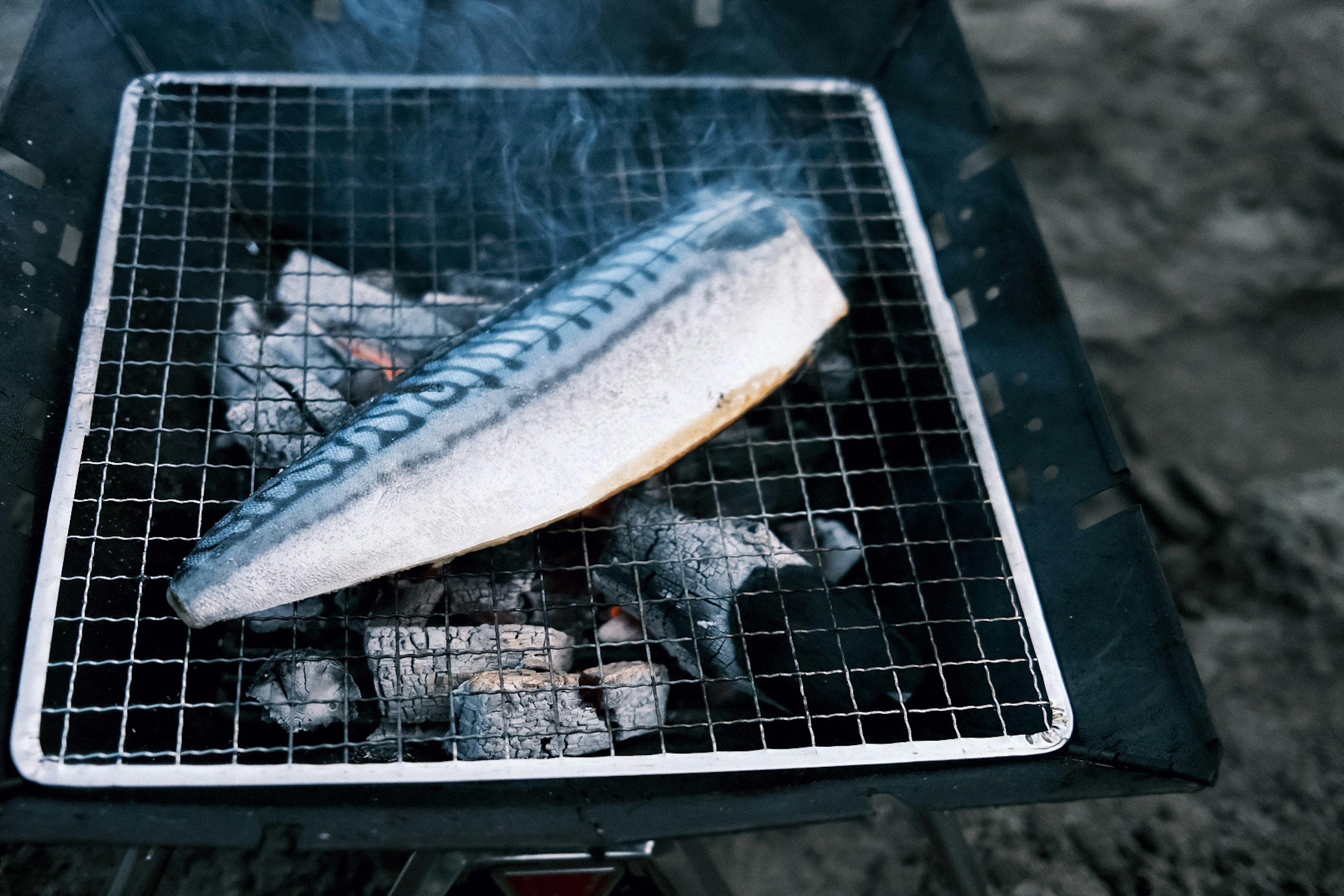 グリルで焼かれているサバのフィレと煙