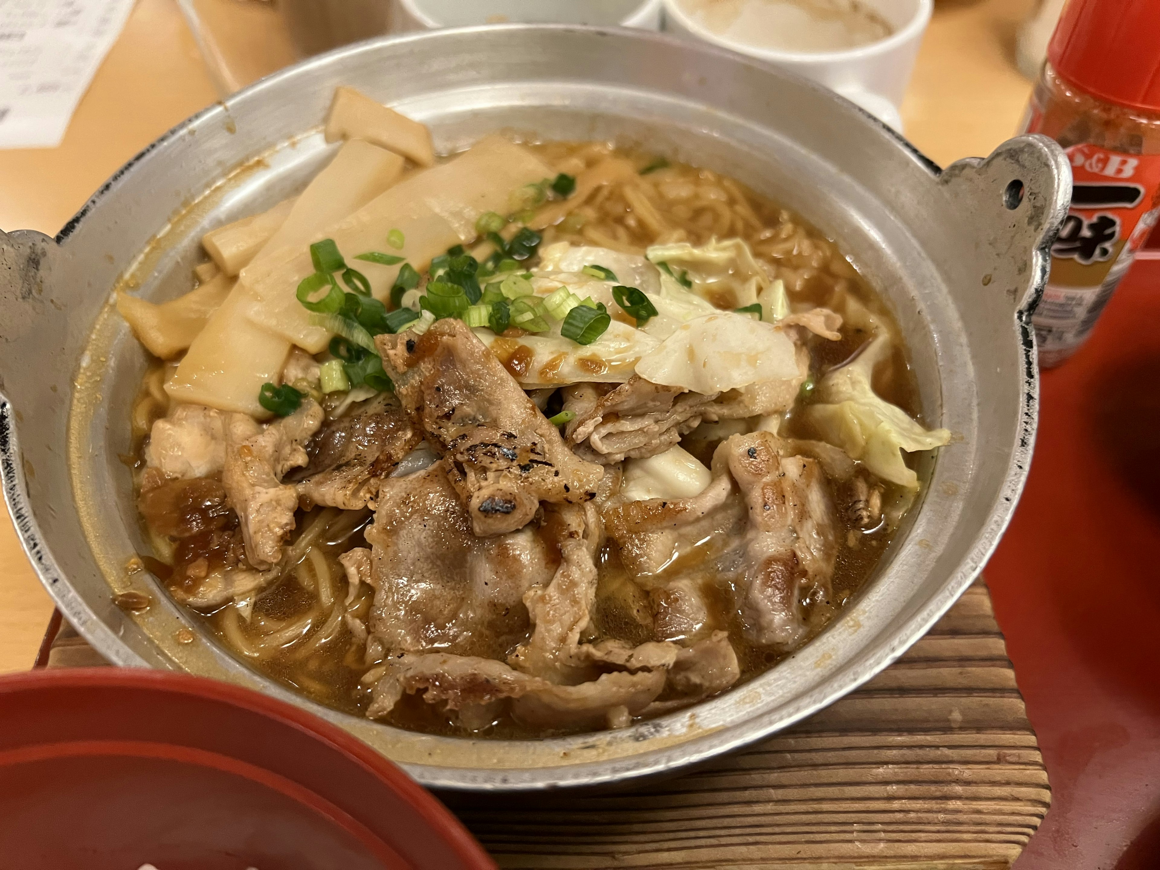 Un plat de fondue avec du porc tranché et des légumes