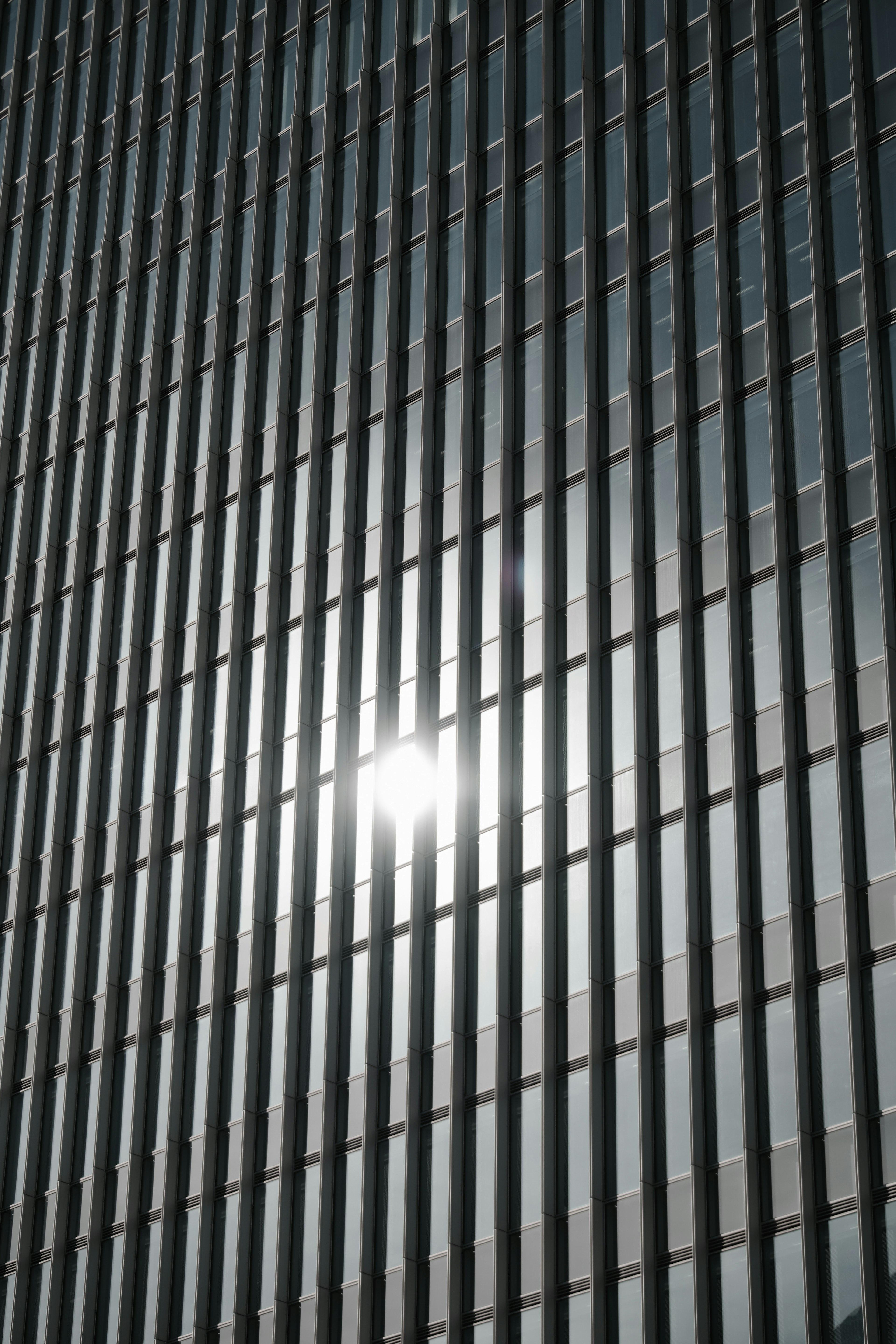 Gebäudefassade mit vertikalen Glasplatten, die Sonnenlicht reflektieren