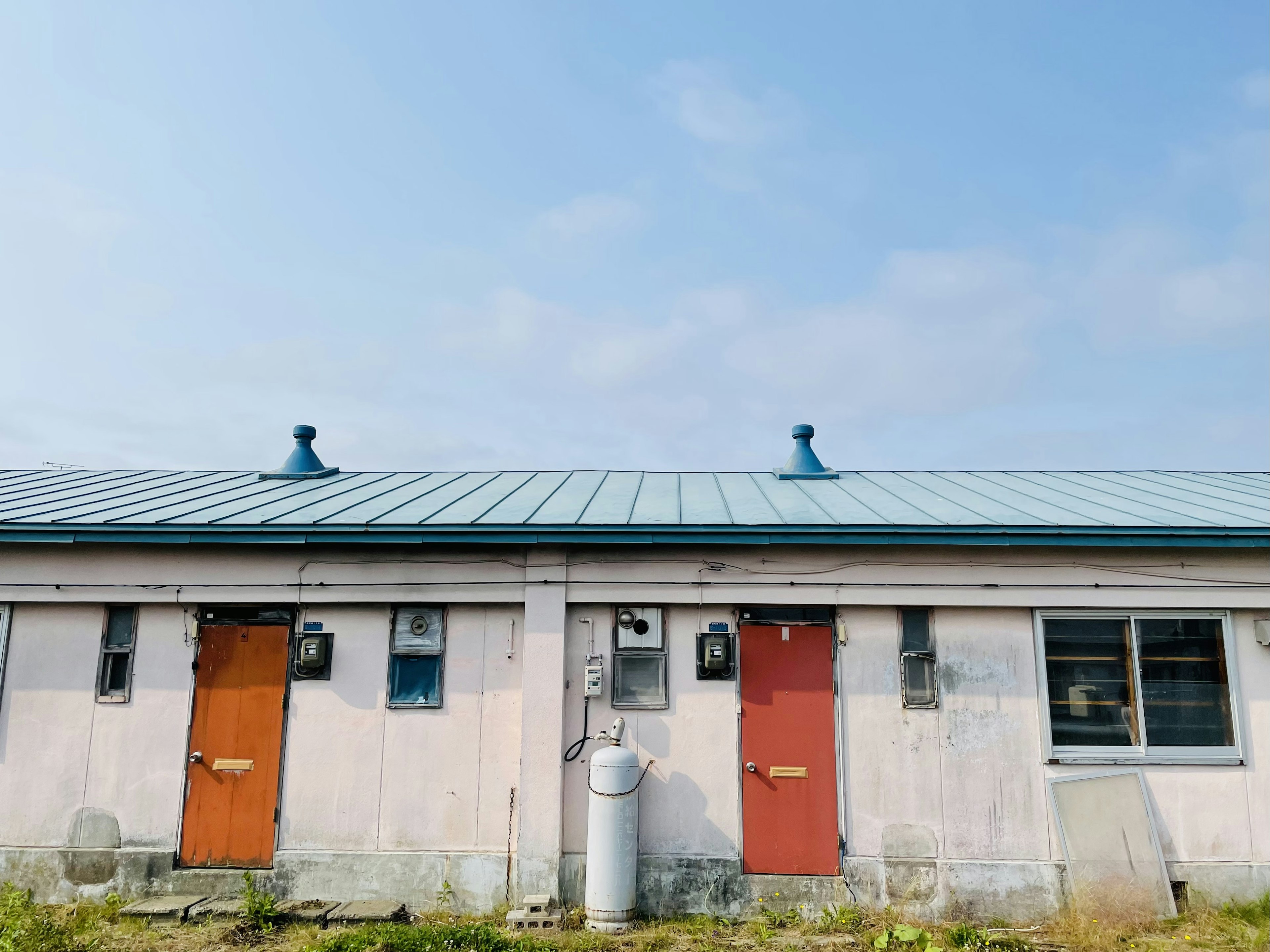 一栋老建筑的外观，蓝色屋顶和两个橙色门