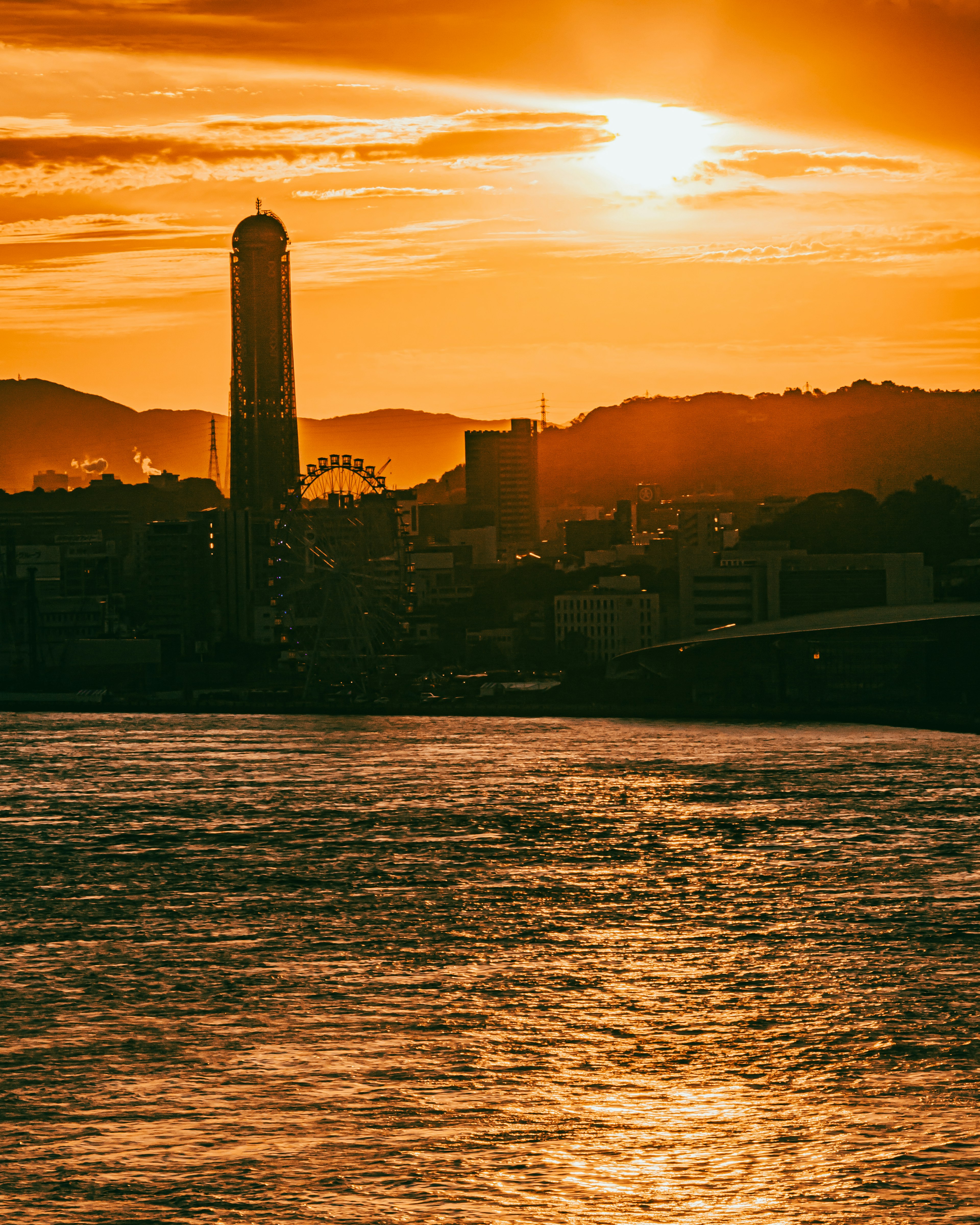 Sonnenuntergang über Kobe mit einem markanten Turm und Uferpromenade