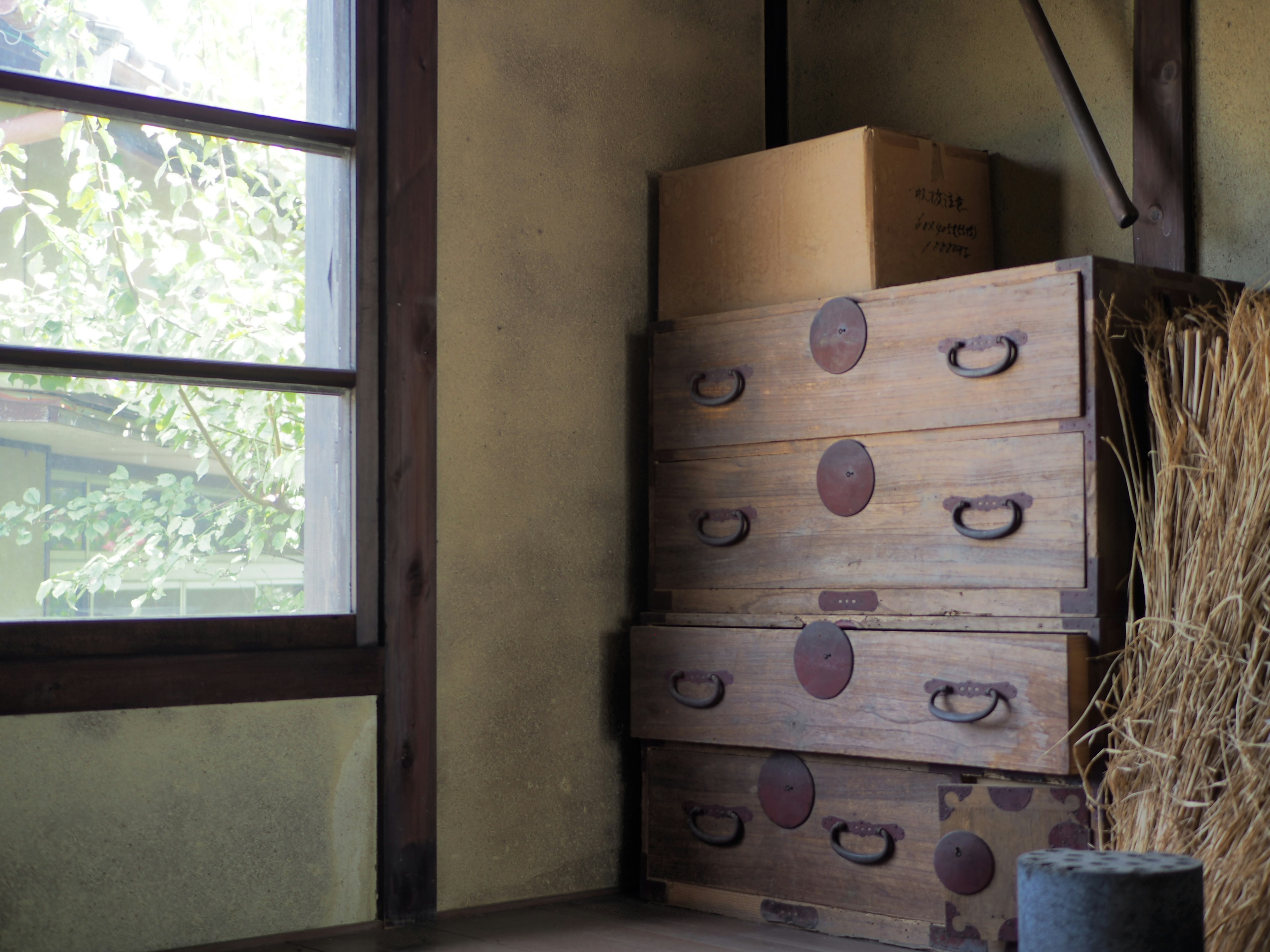 Coin d'une pièce avec des tiroirs en bois empilés à côté d'une fenêtre et d'une boîte en carton