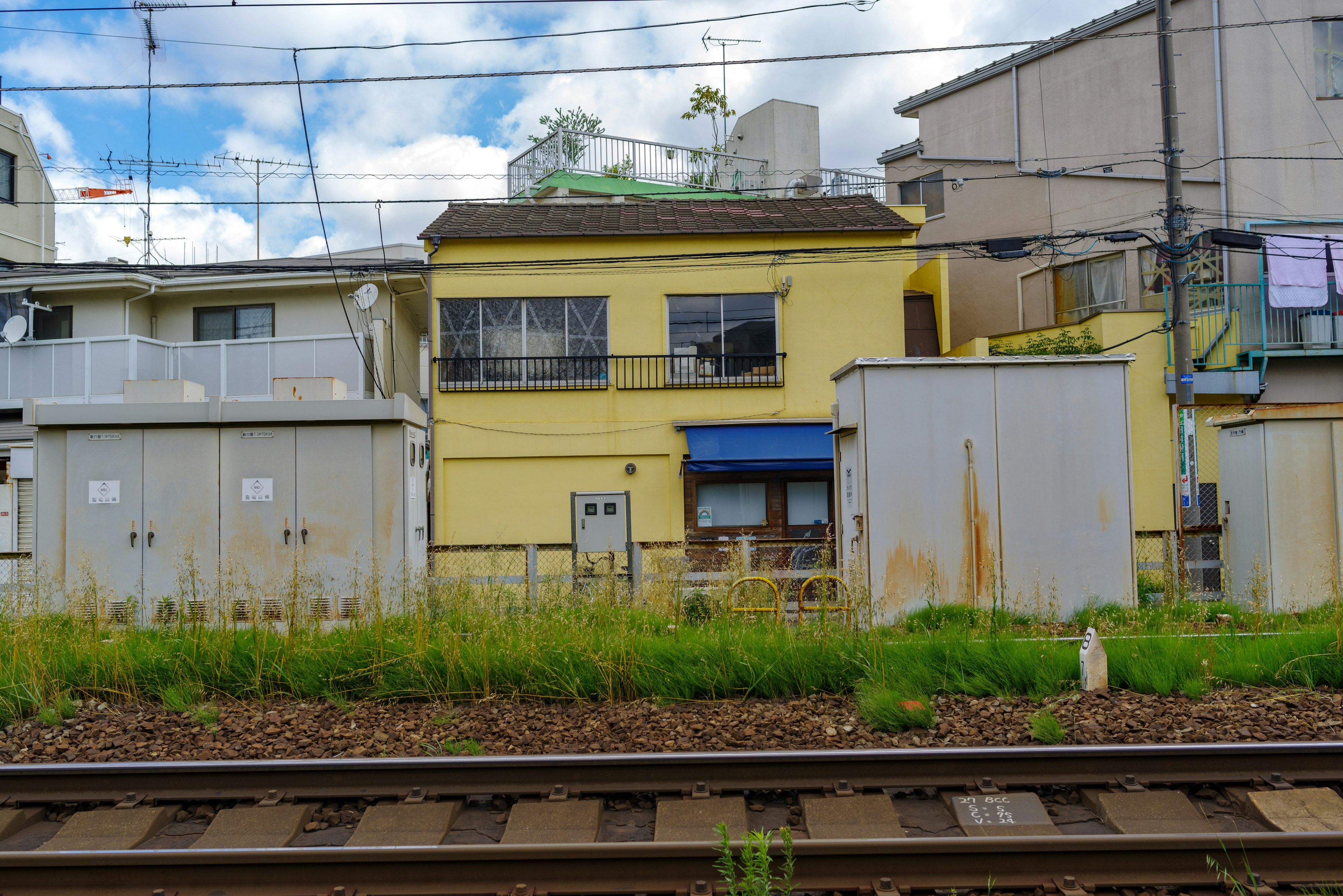 Maison jaune près des voies ferrées avec des bâtiments environnants