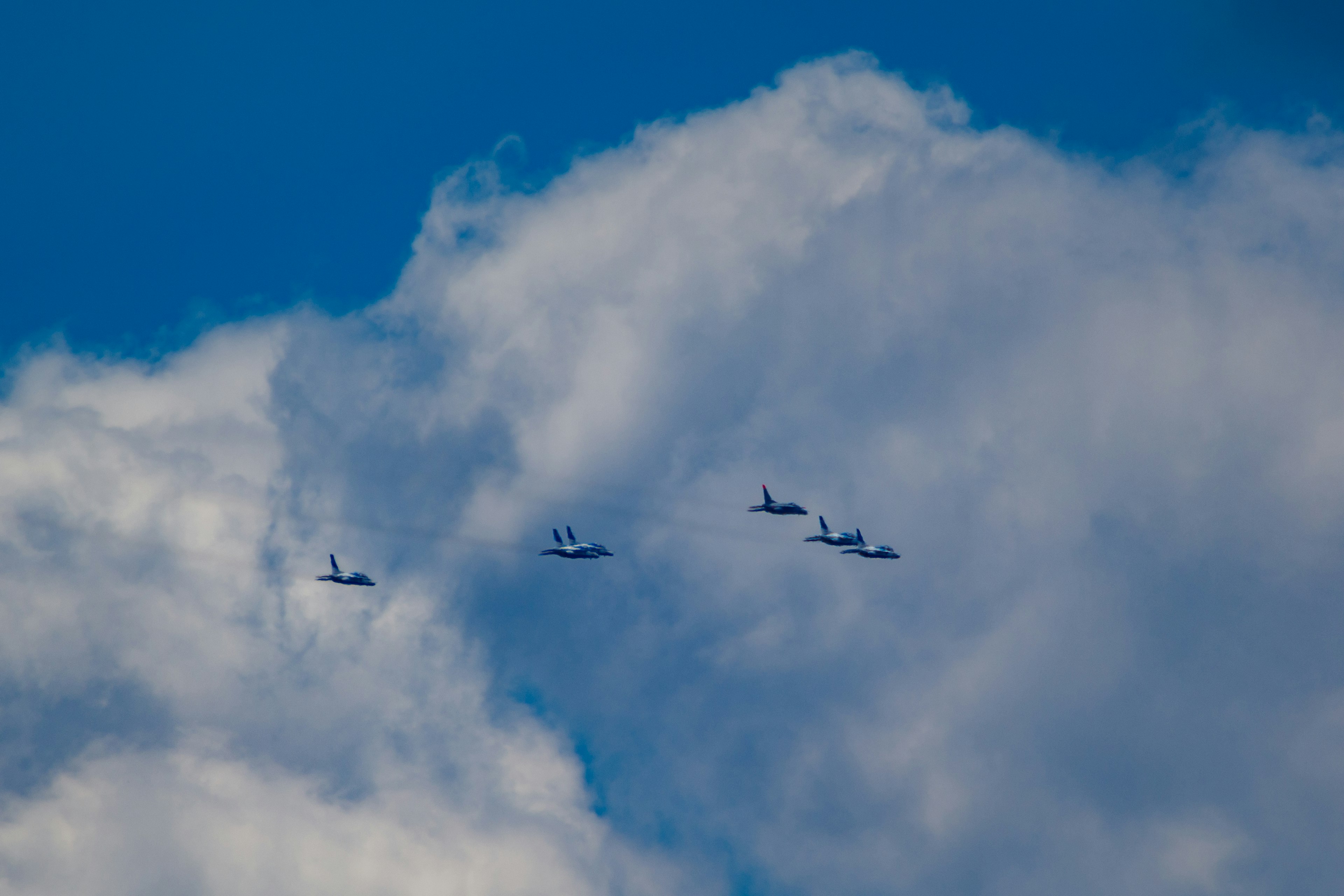 Multiple airplanes flying among white clouds in a blue sky