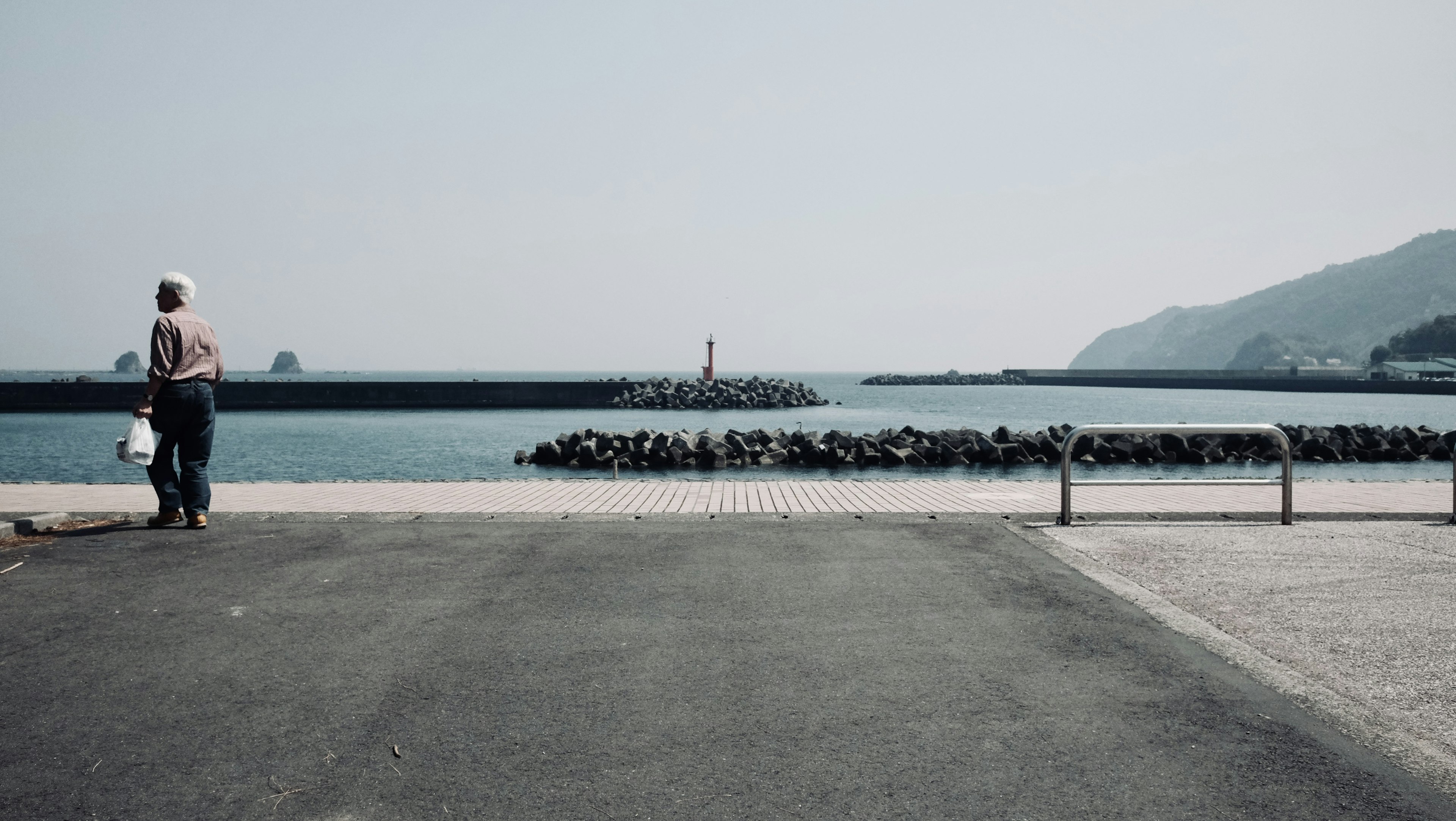 A person standing on the coast with a view of a lighthouse