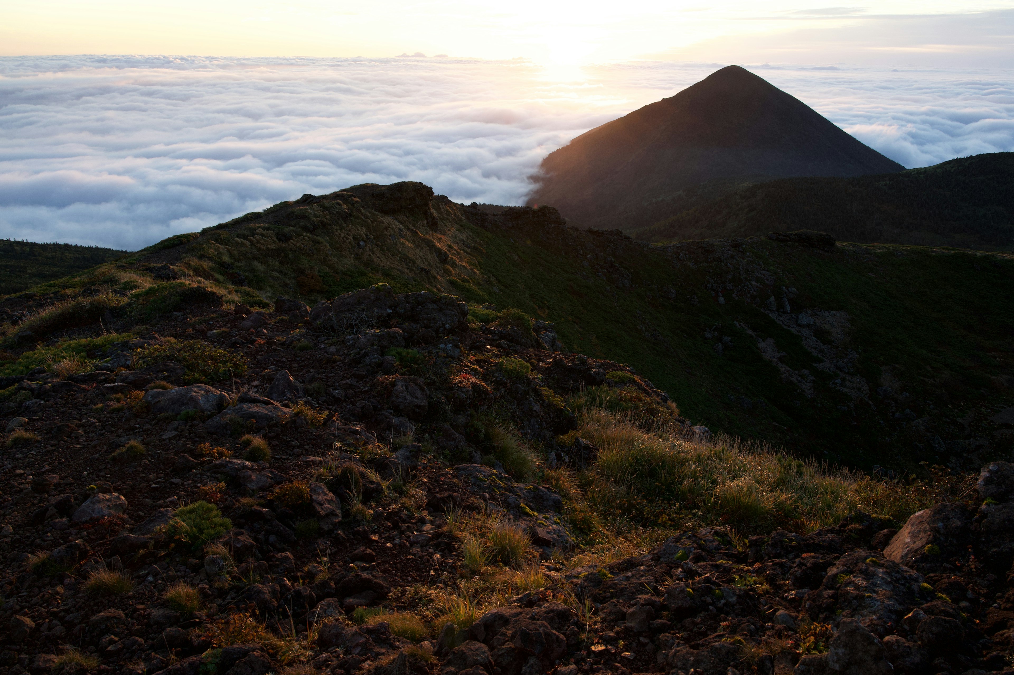 Silhouette d'une montagne au coucher du soleil au-dessus d'une mer de nuages