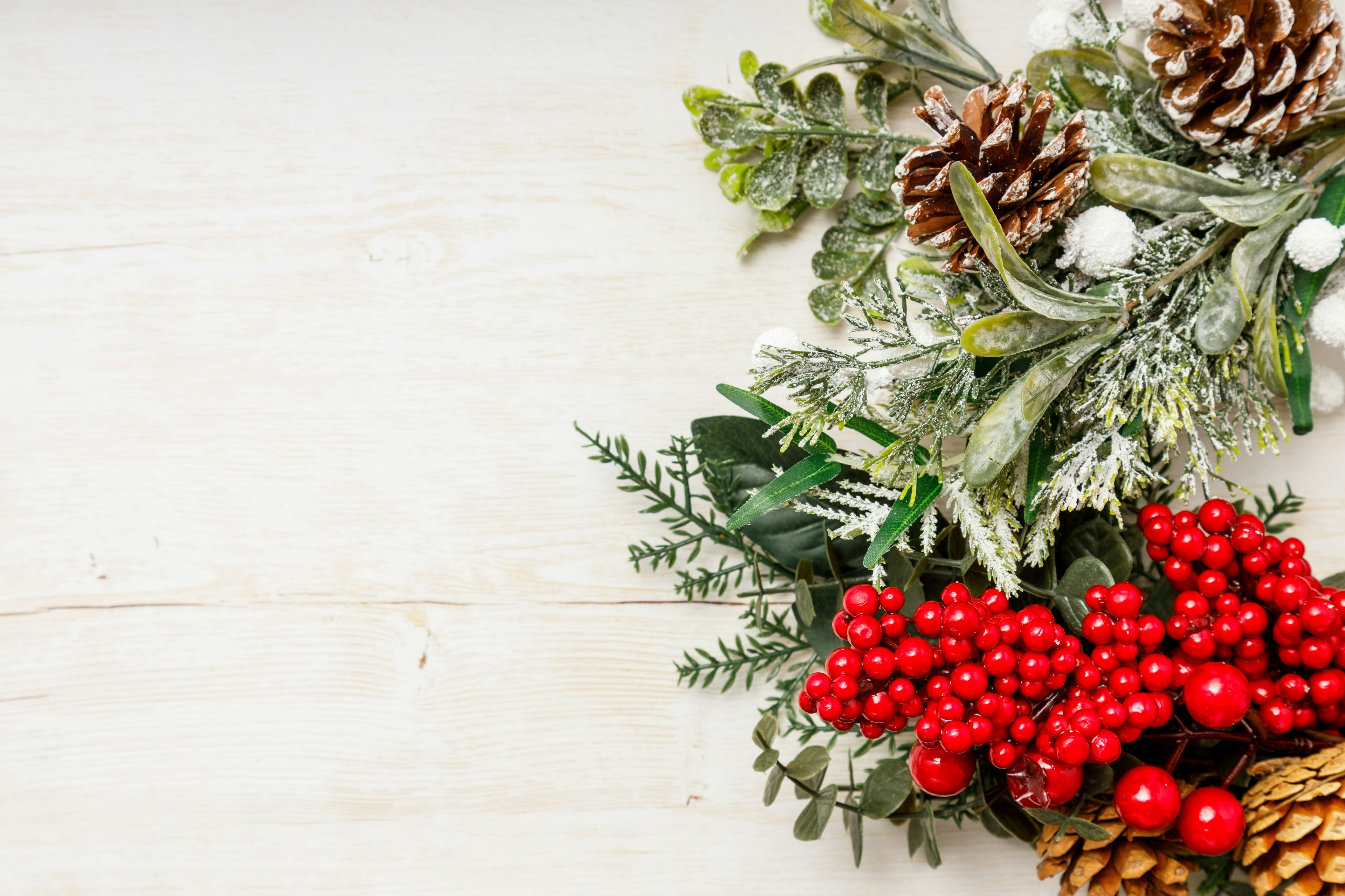 Weihnachtsdekoration mit Tannenzapfen und roten Beeren im grünen Laub