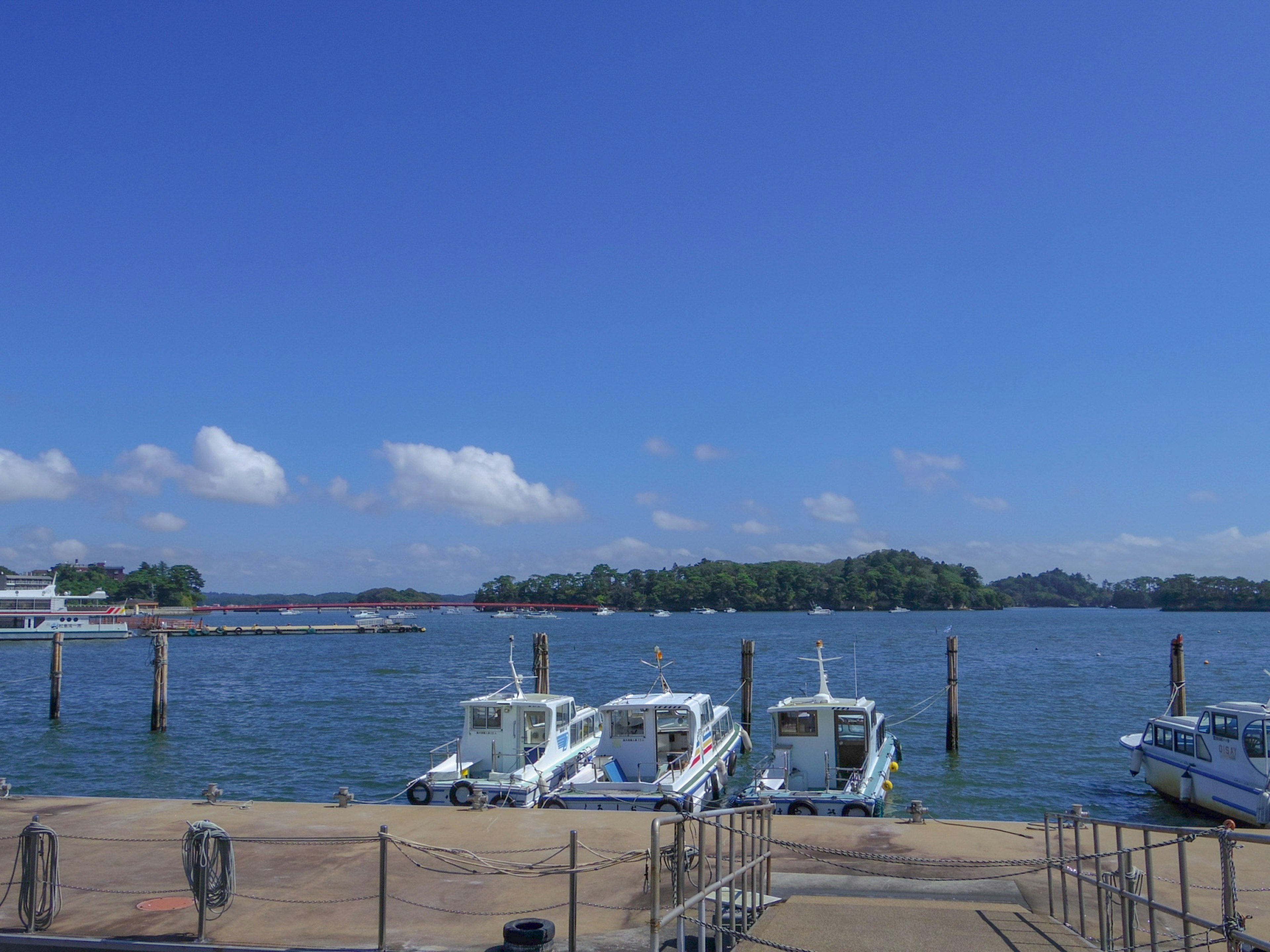 Puerto con botes bajo un cielo azul y nubes blancas