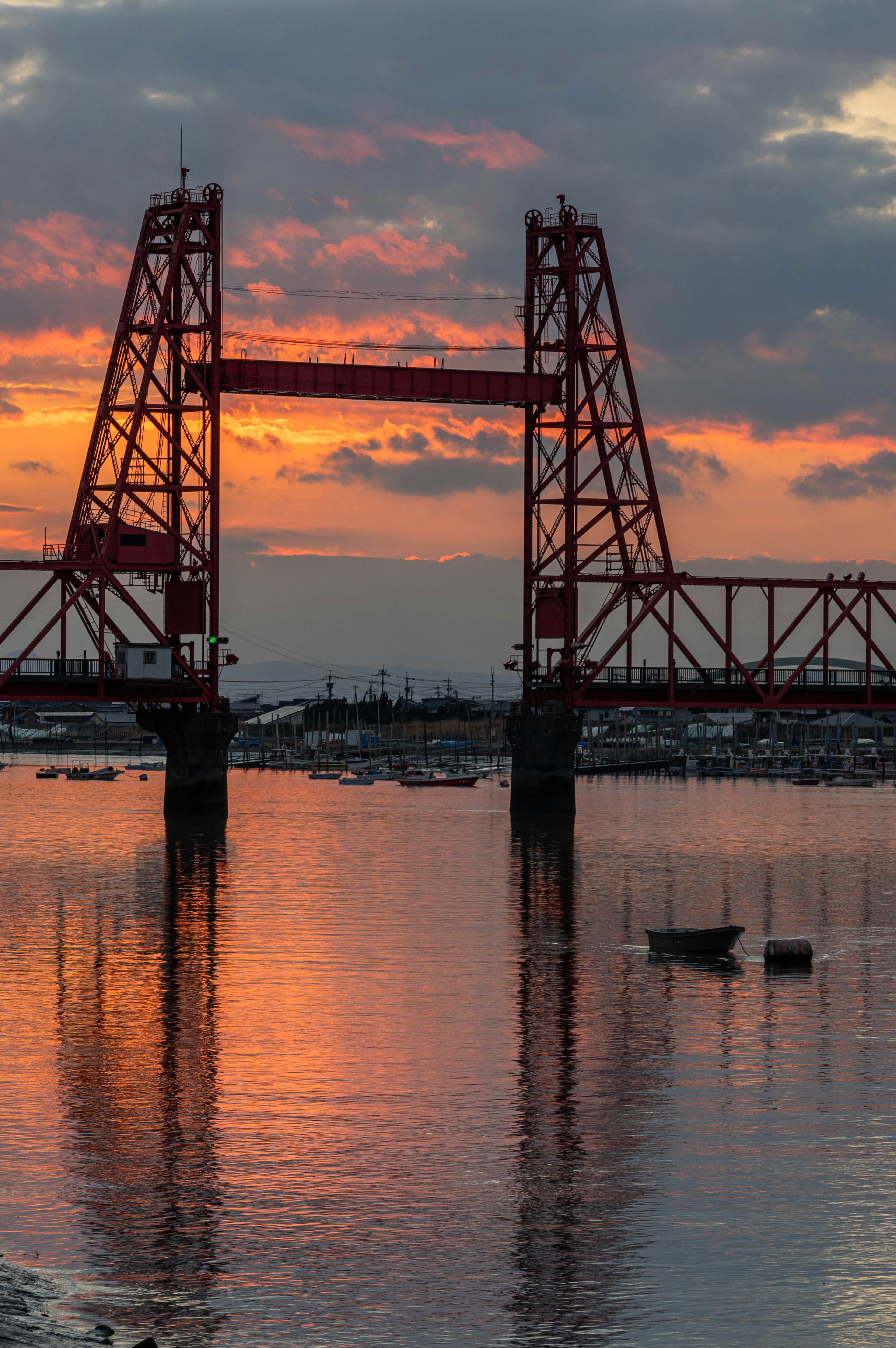 Rote Brücke silhouettiert gegen einen Sonnenuntergang, der sich im Wasser spiegelt