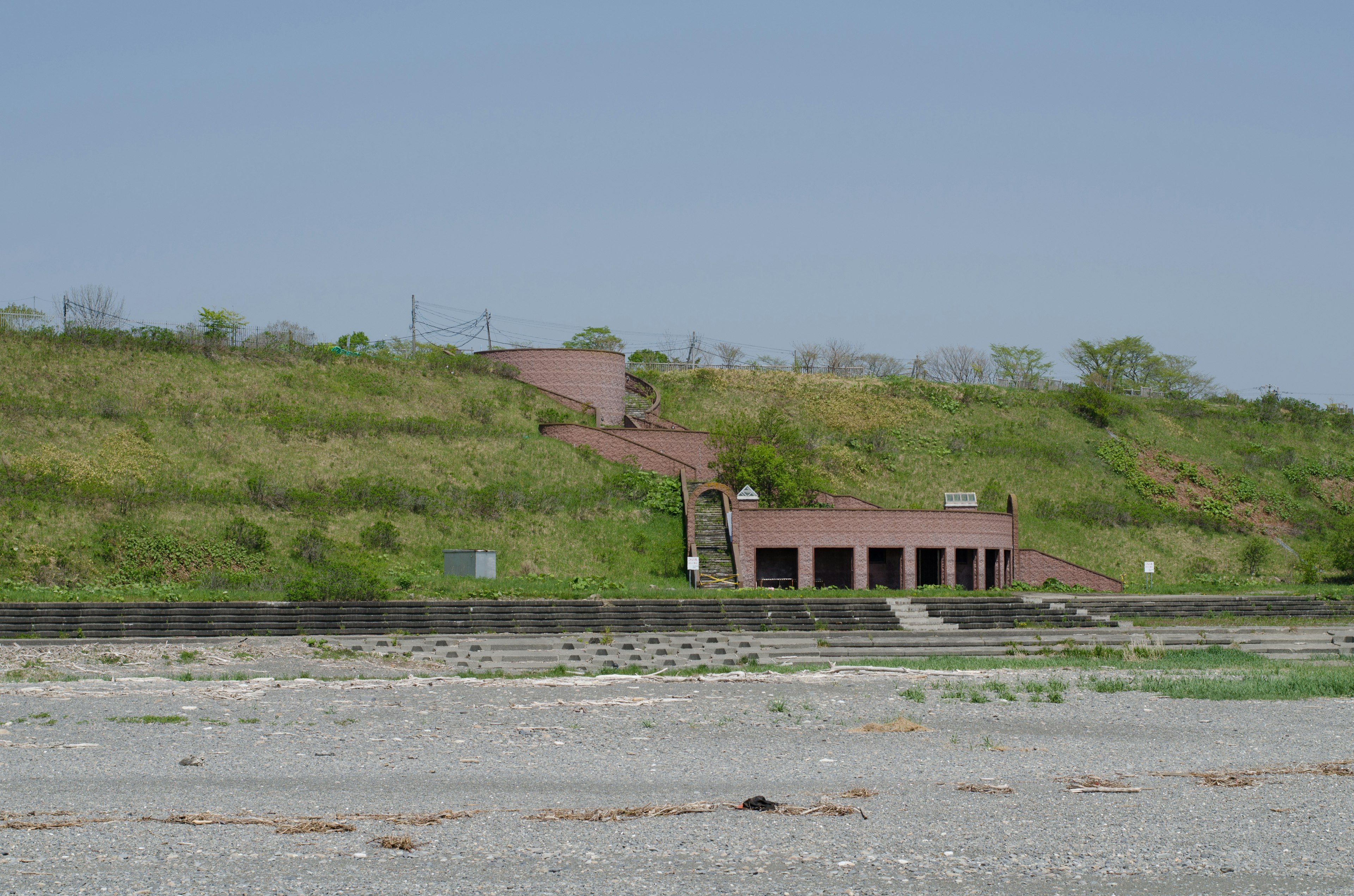 緑の丘の上にある赤いレンガの建物と階段