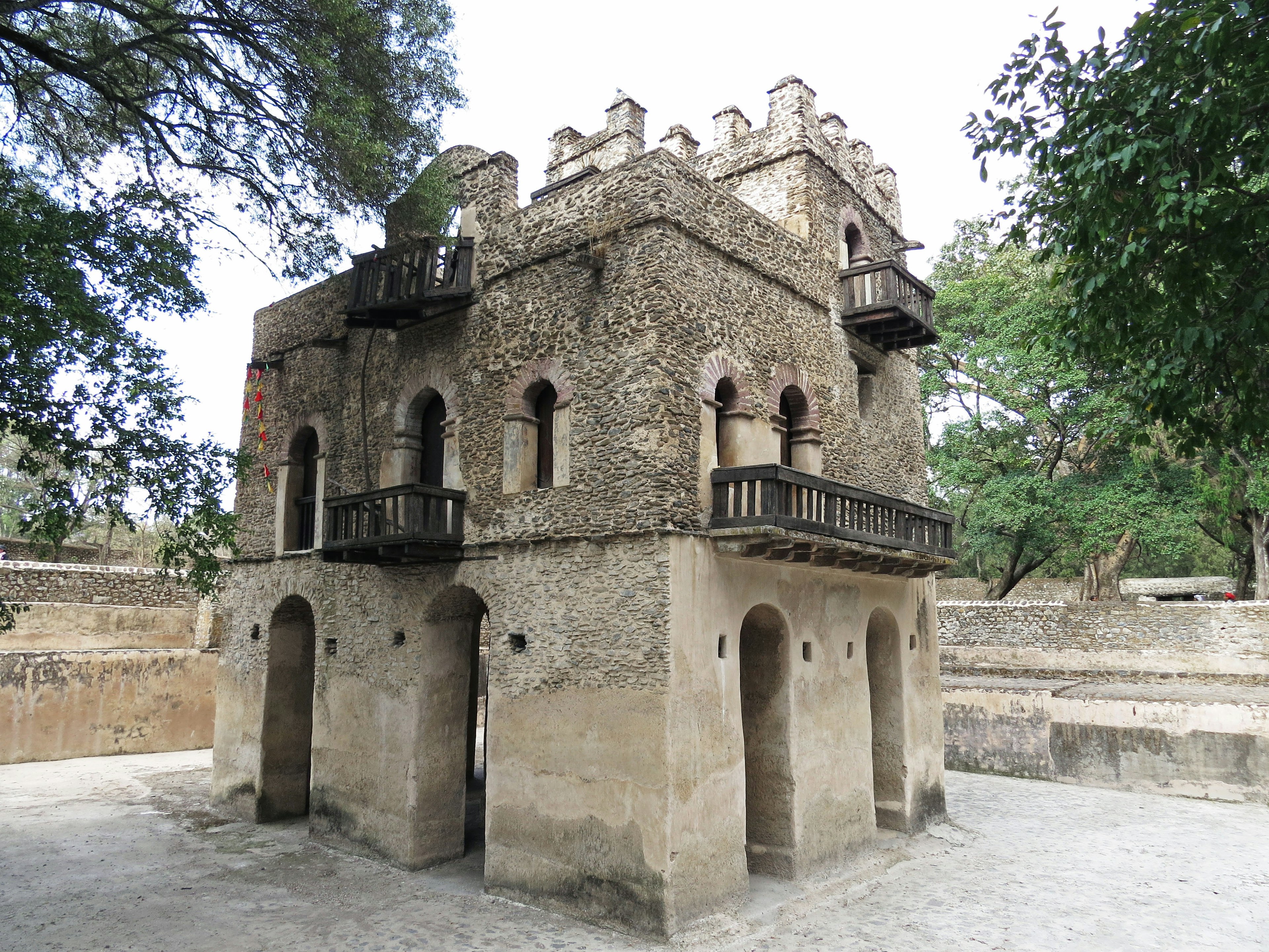 Old stone building with balconies surrounded by green trees