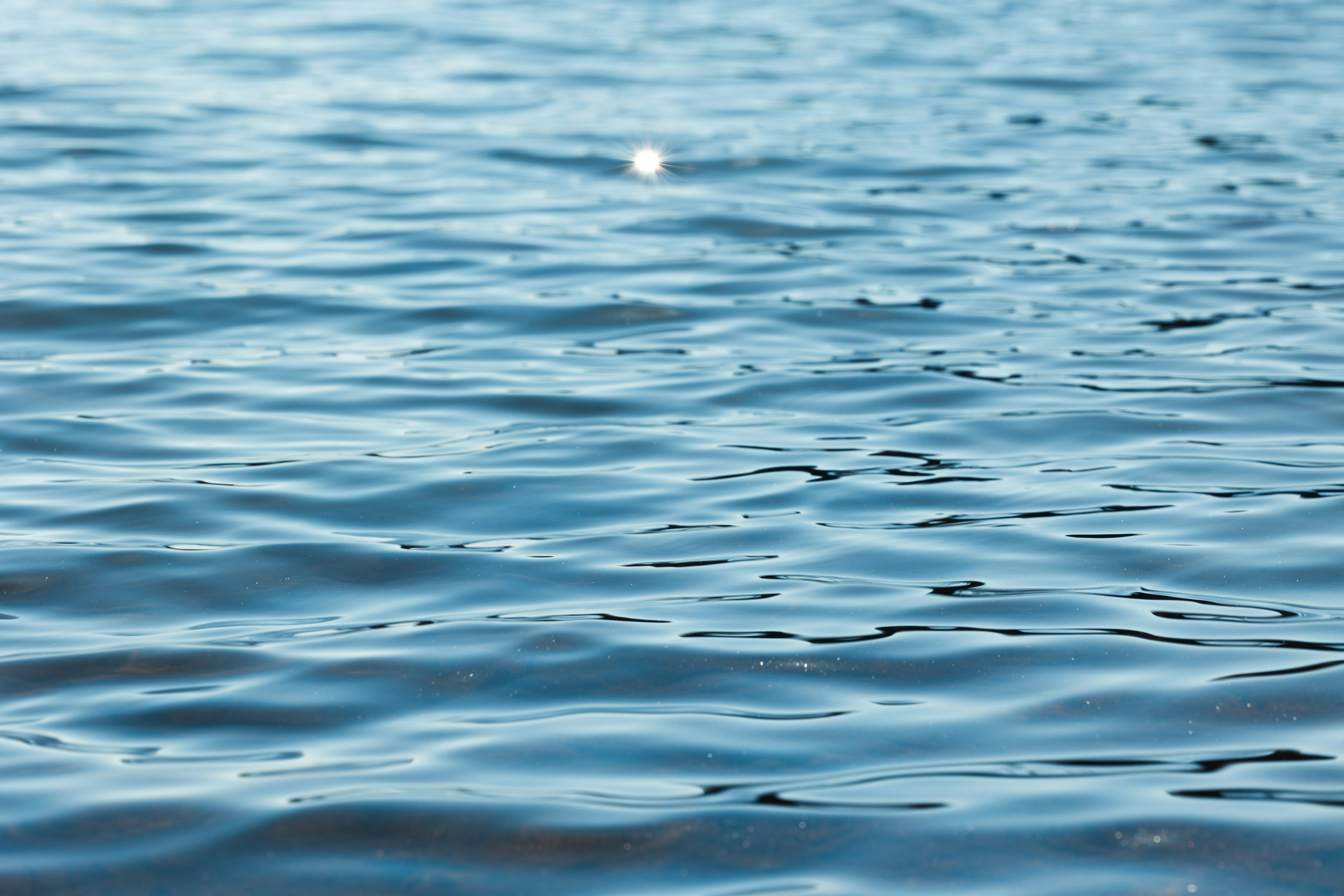 Surface d'eau bleue ondulante avec des reflets de lumière