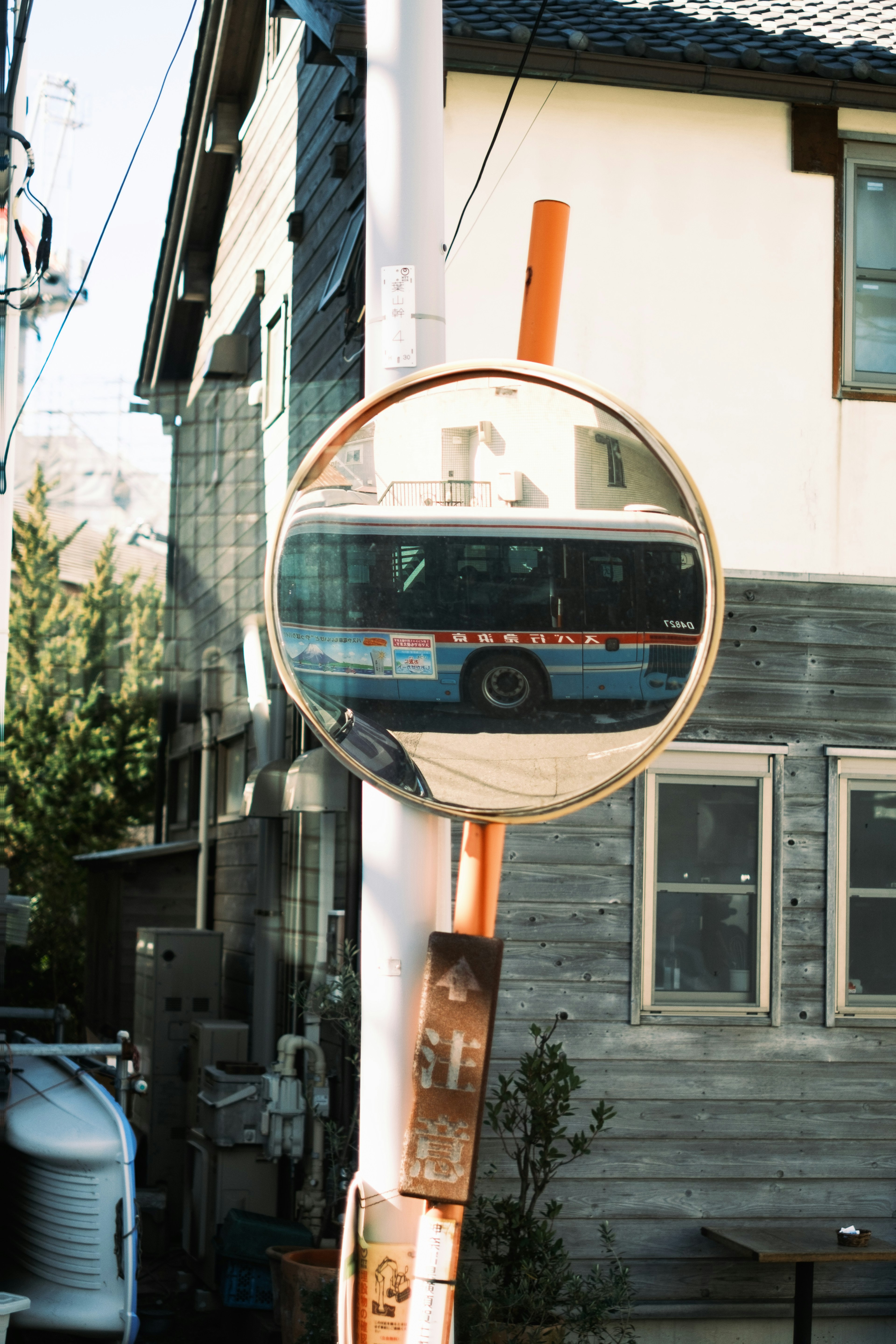 Un autobús reflejado en un espejo convexo con un edificio de fondo