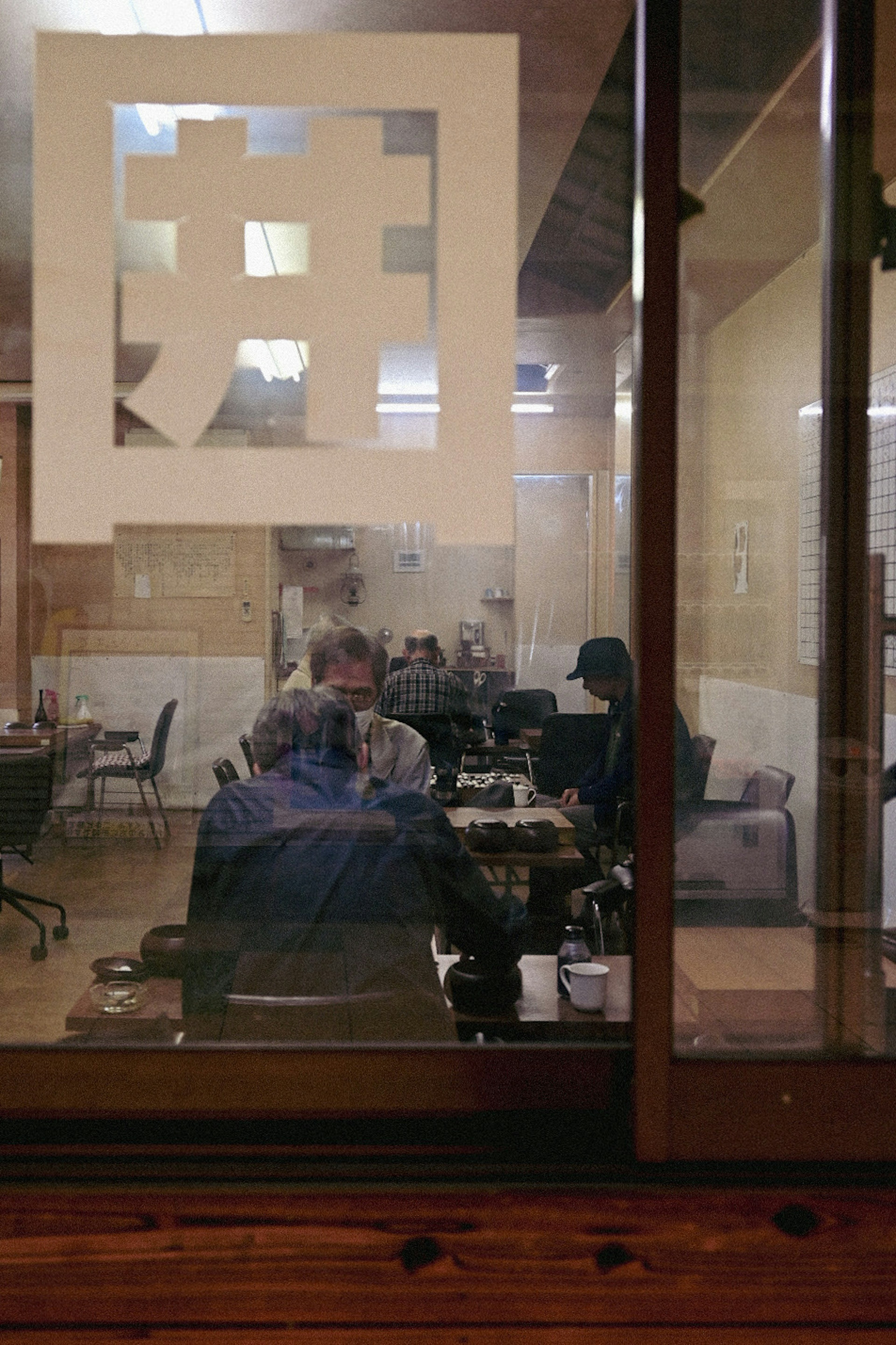 Office interior visible through glass with people working