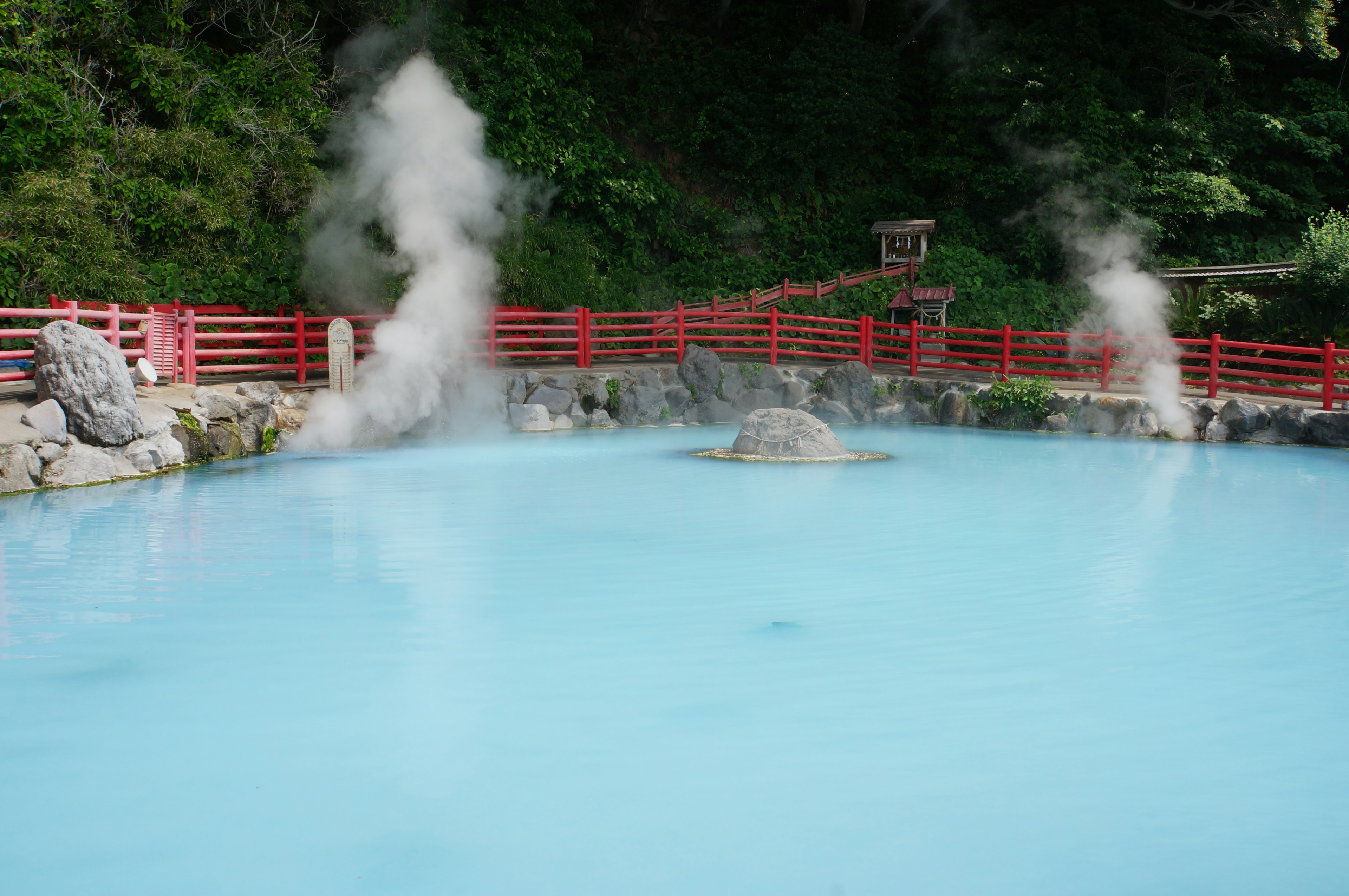 Vue pittoresque d'une source chaude bleue entourée d'une clôture en bois rouge