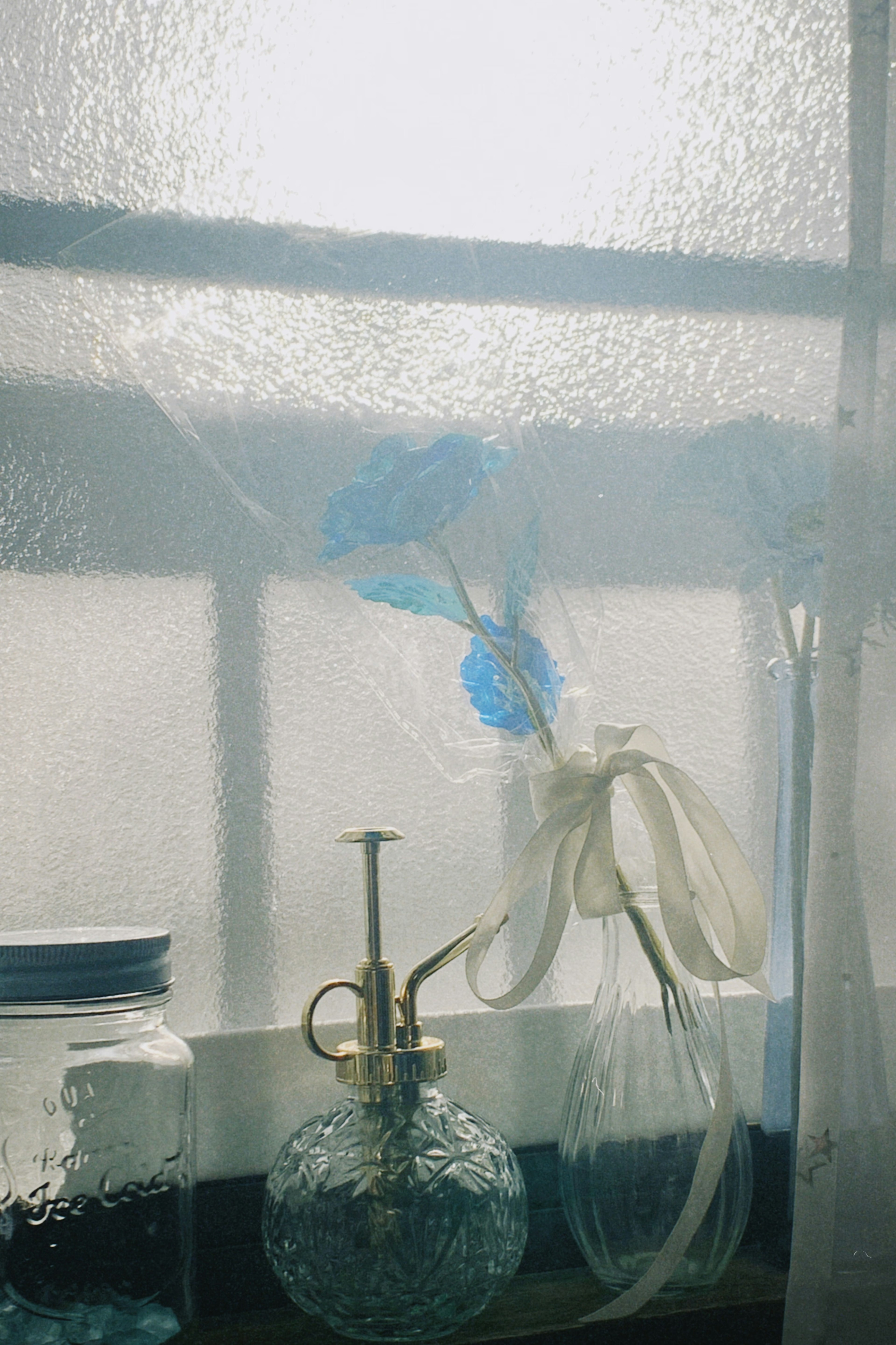 Una escena de ventana con una botella decorada con flores azules y una botella de perfume