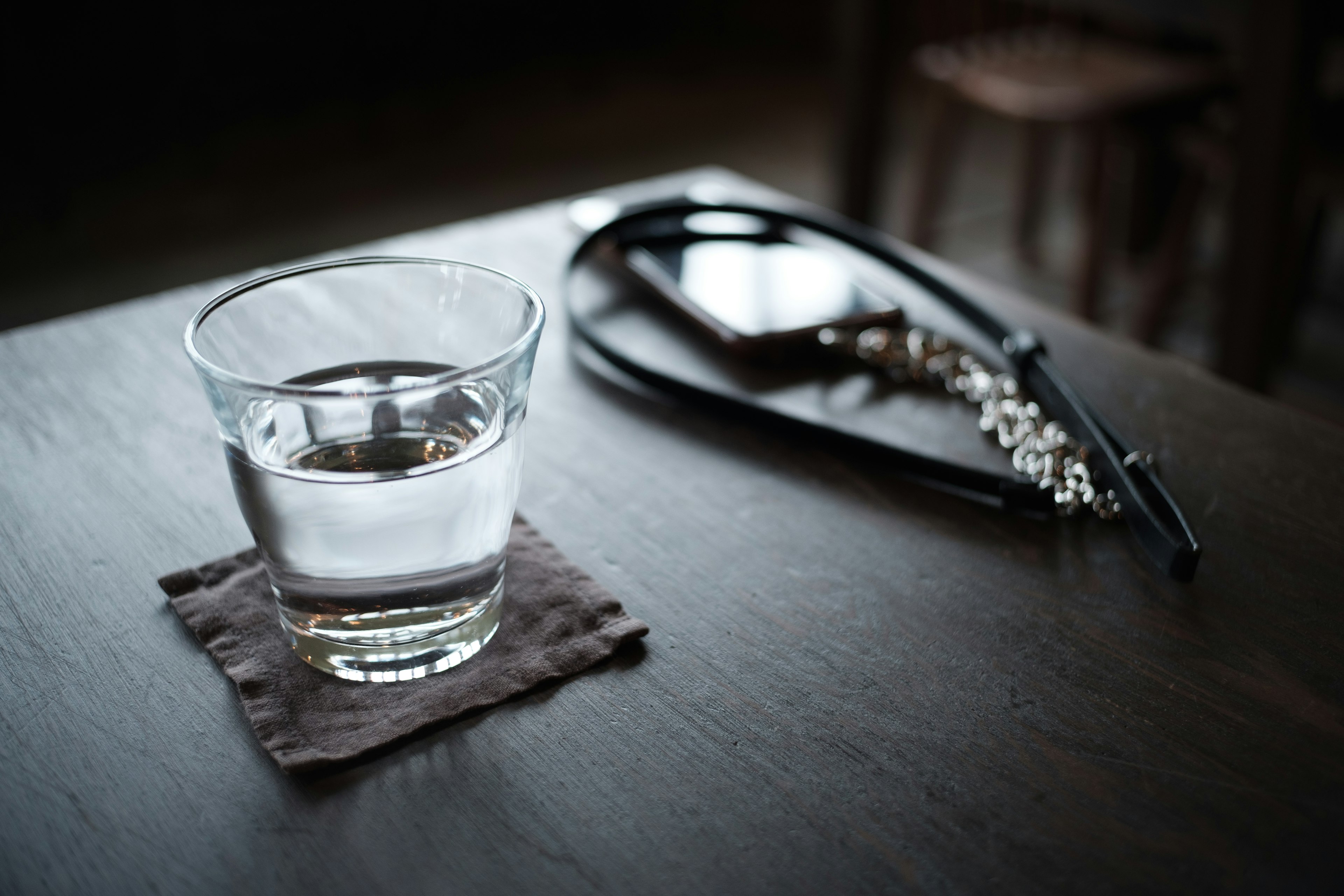 Un vaso de agua sobre una mesa con auriculares negros al lado