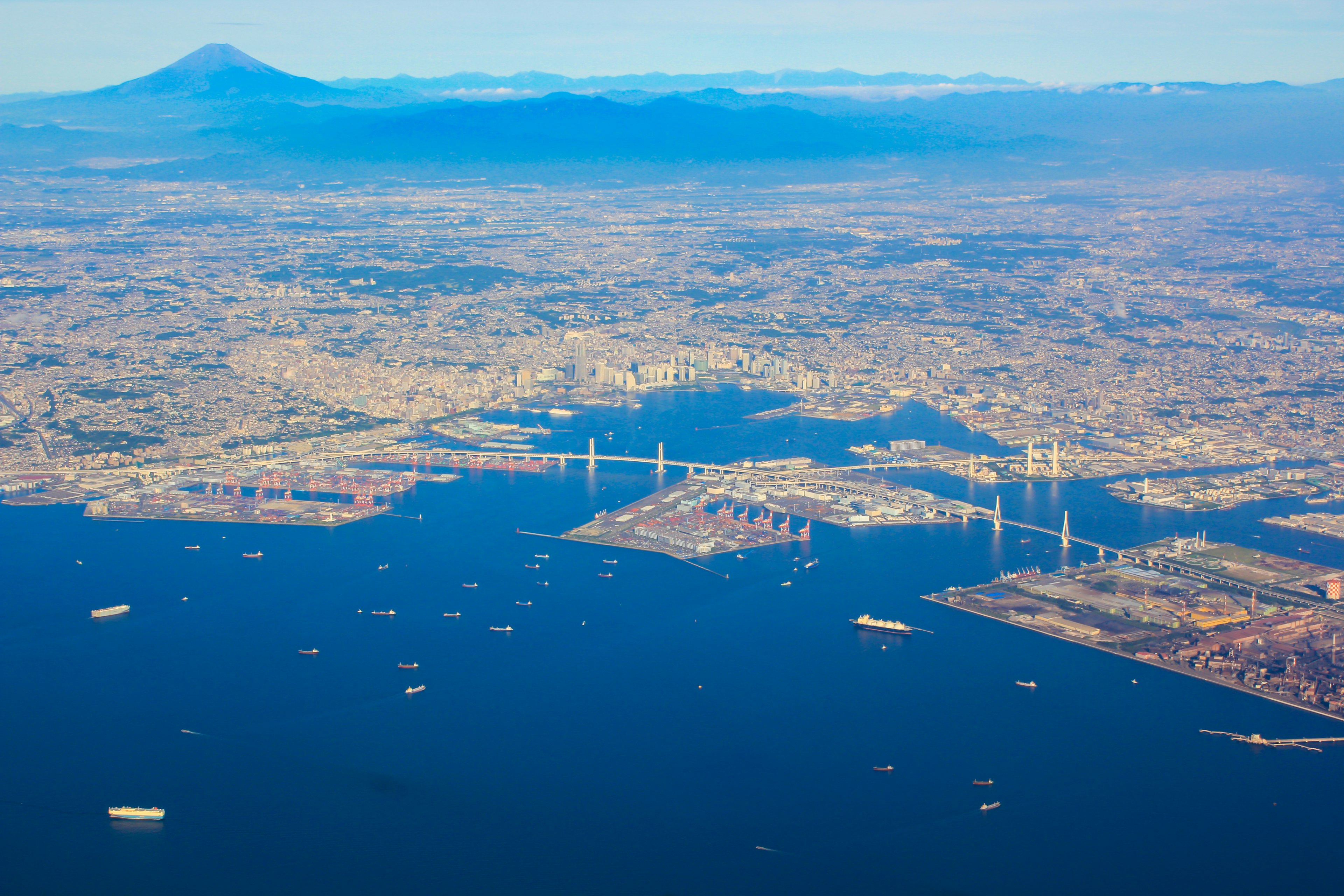 Aerial view of a city and harbor with Mount Fuji in the distance