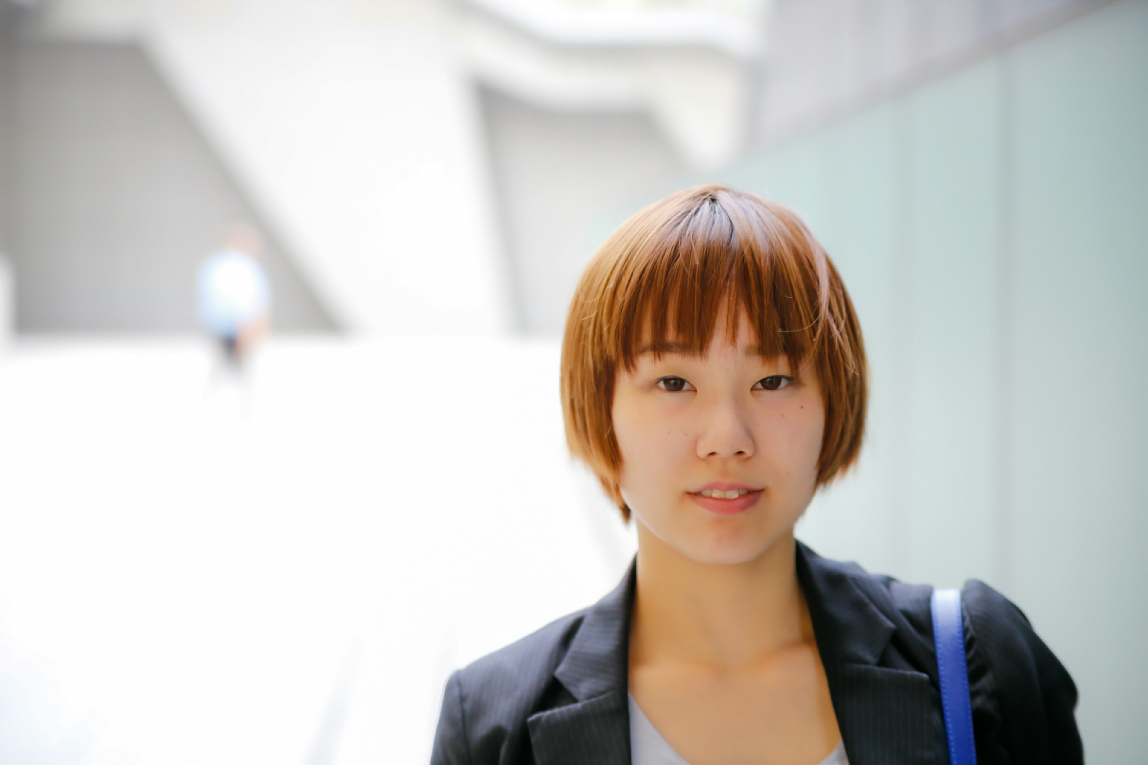 Femme souriante aux cheveux courts en tenue professionnelle avec un fond lumineux