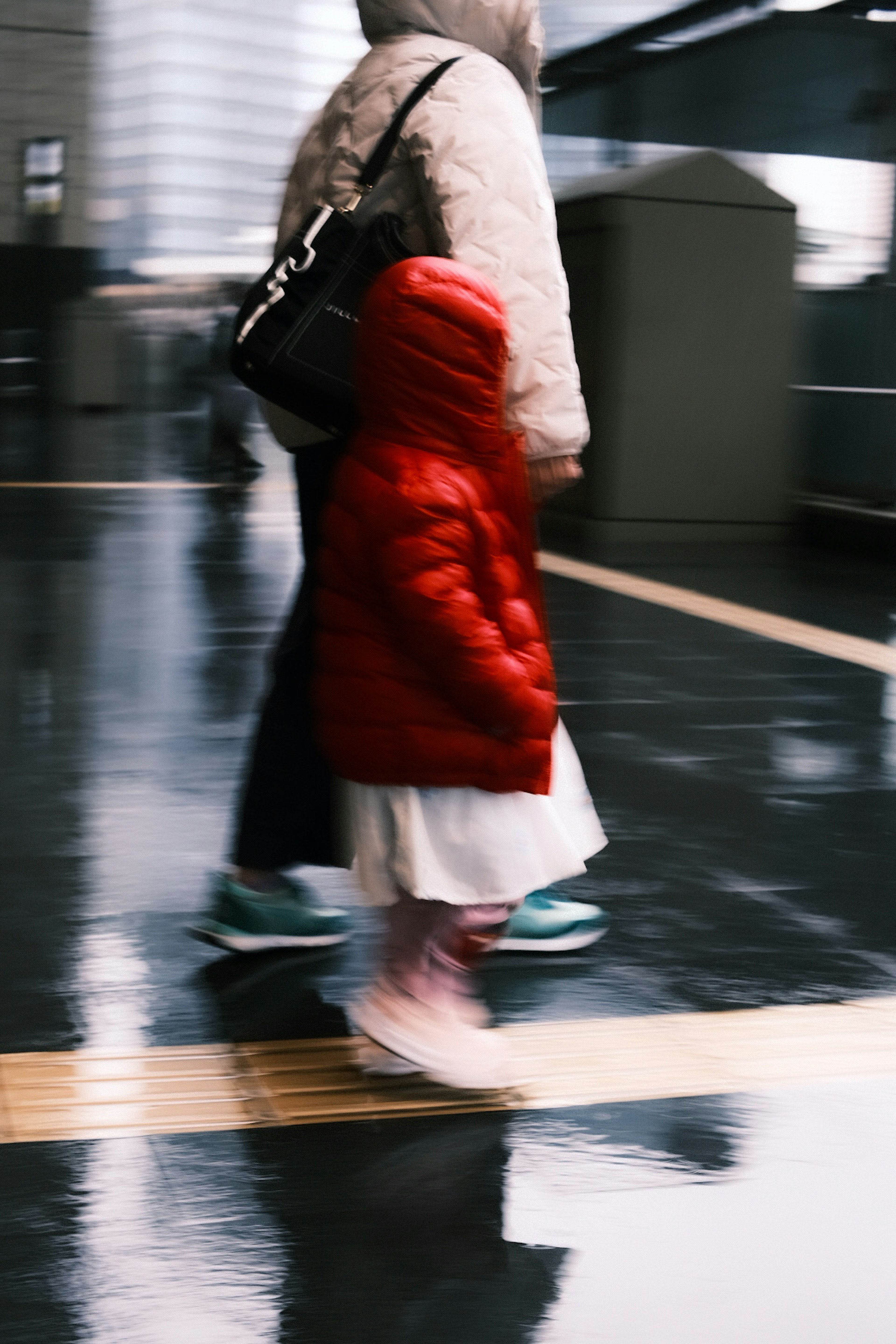 赤いダウンジャケットを着た子供と親が歩いている雨の日のシーン