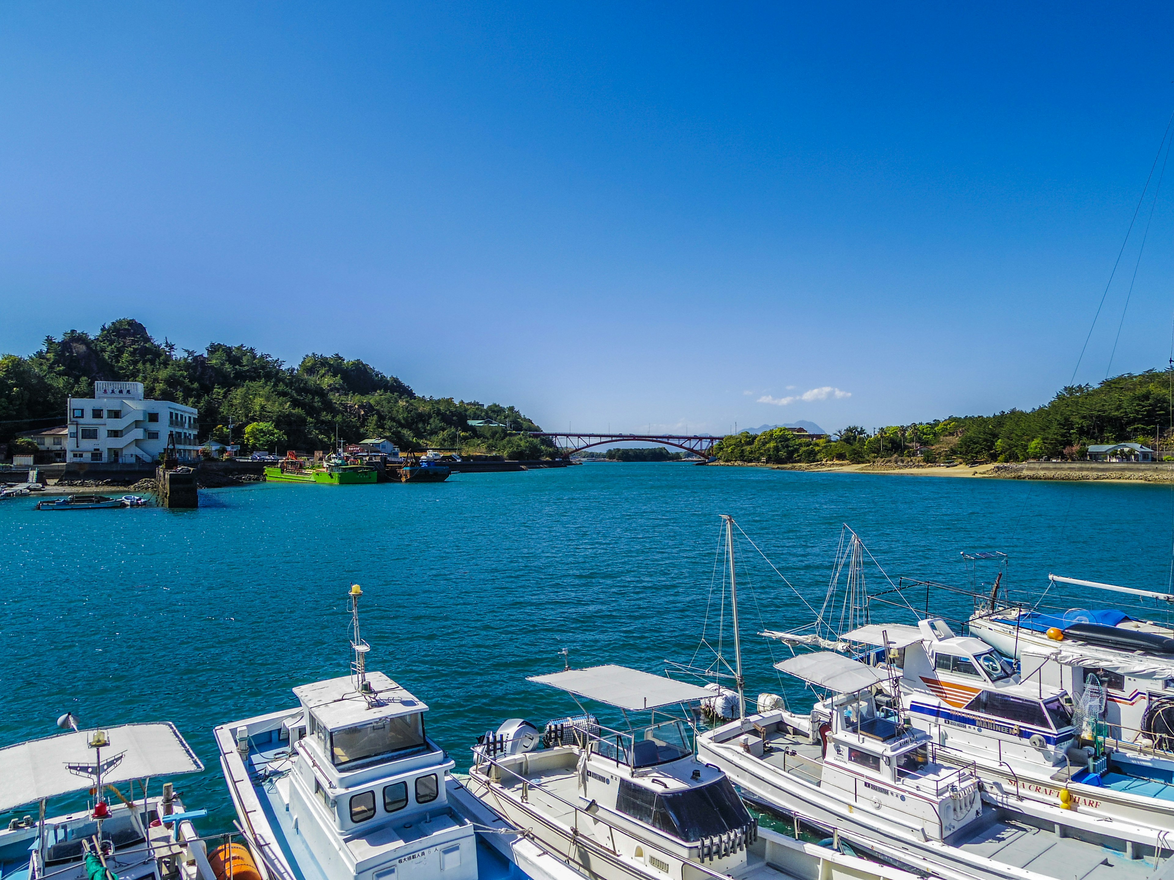 Scenic view of blue water with white boats and a bridge in the background