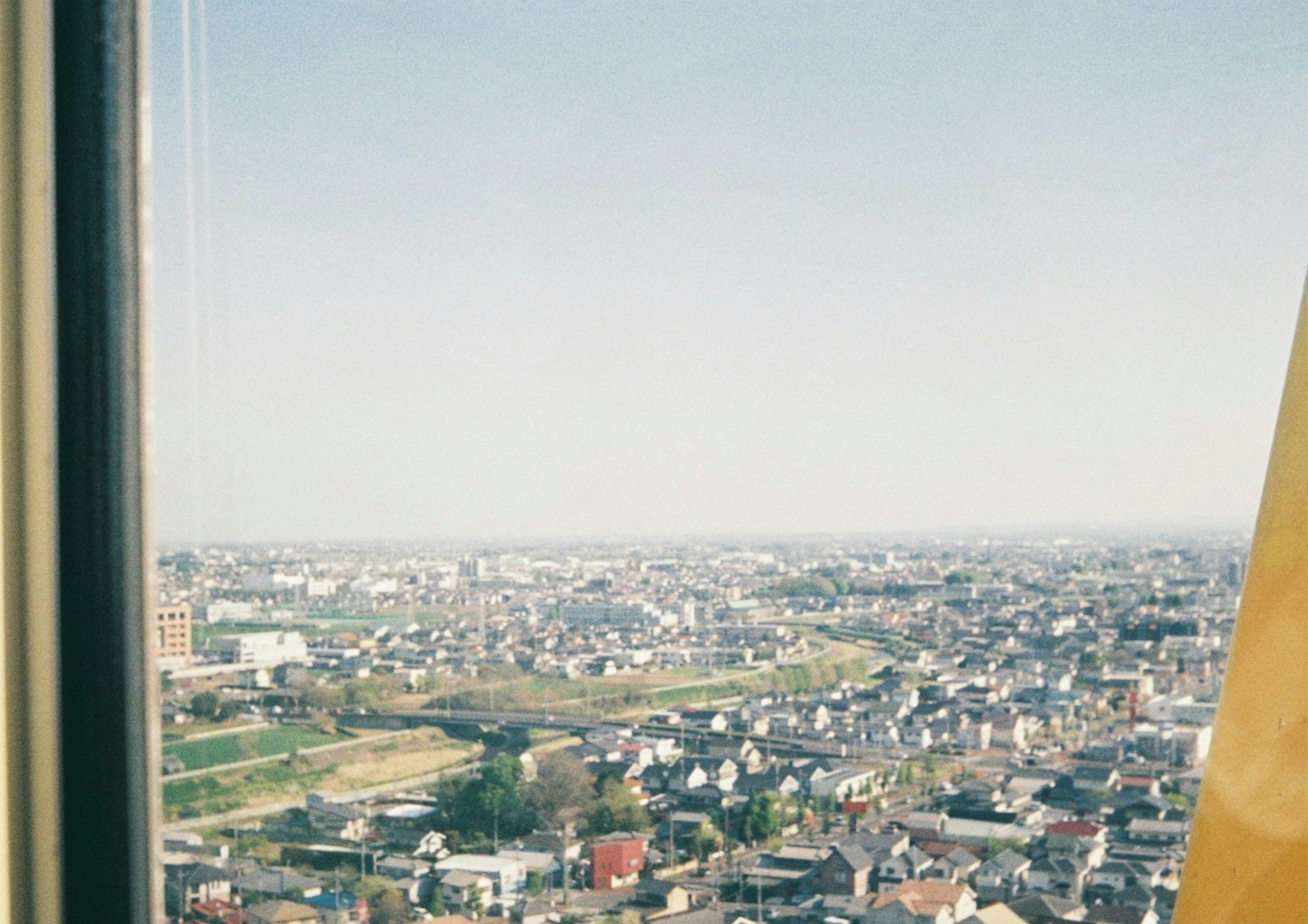 Urban landscape viewed from a high-rise window featuring clear sky and residential areas