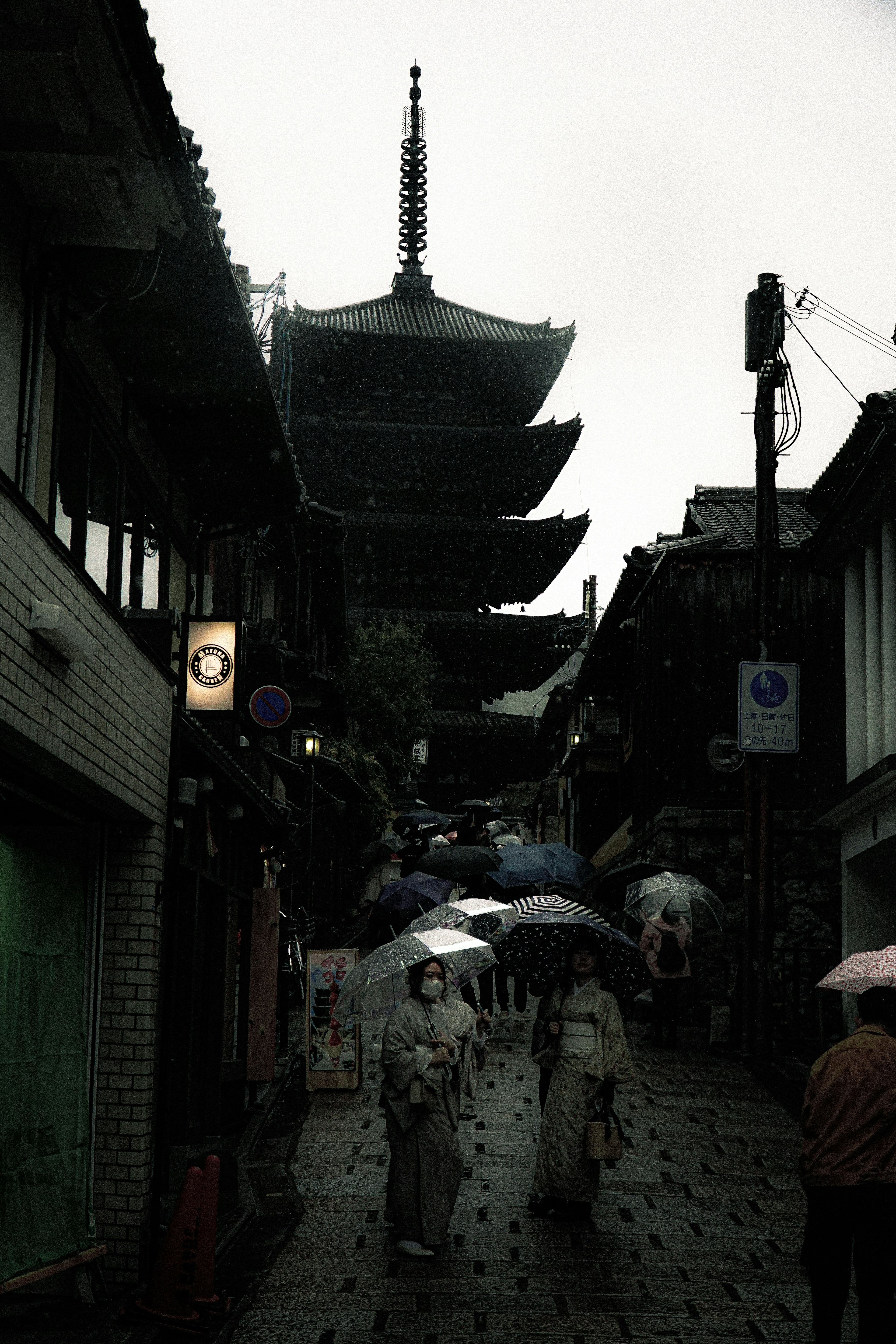 People walking in the rain with umbrellas near a pagoda