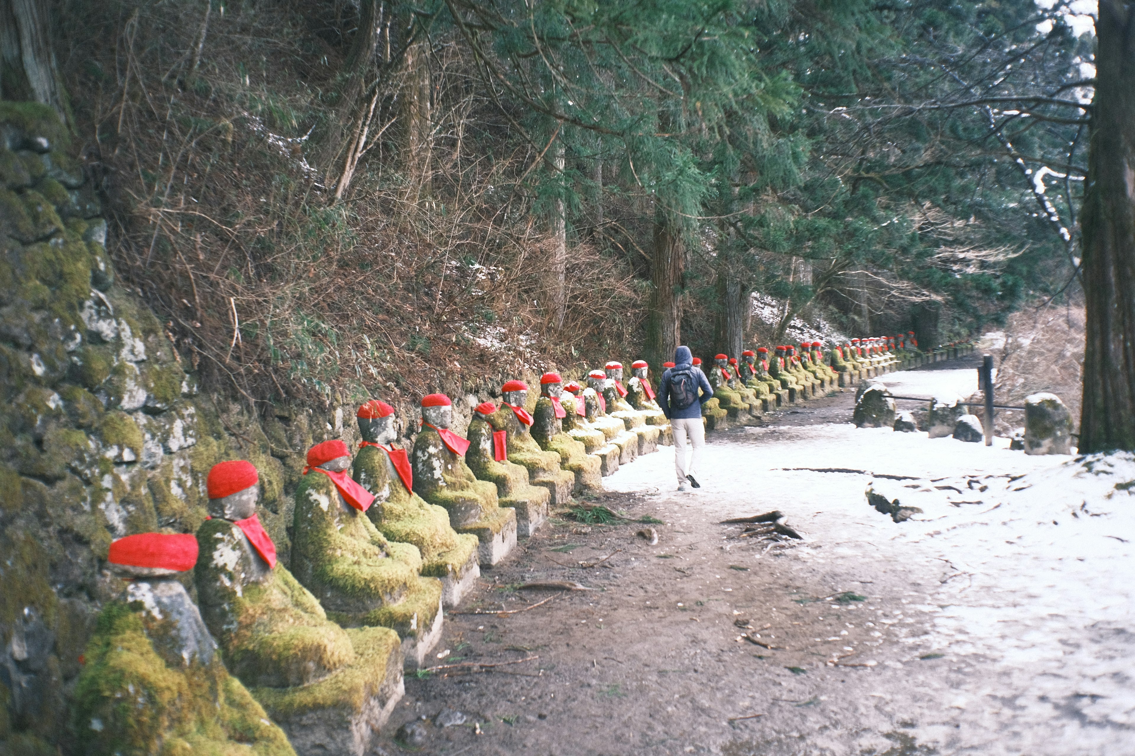 Un camino bordeado de estatuas de piedra con sombreros rojos