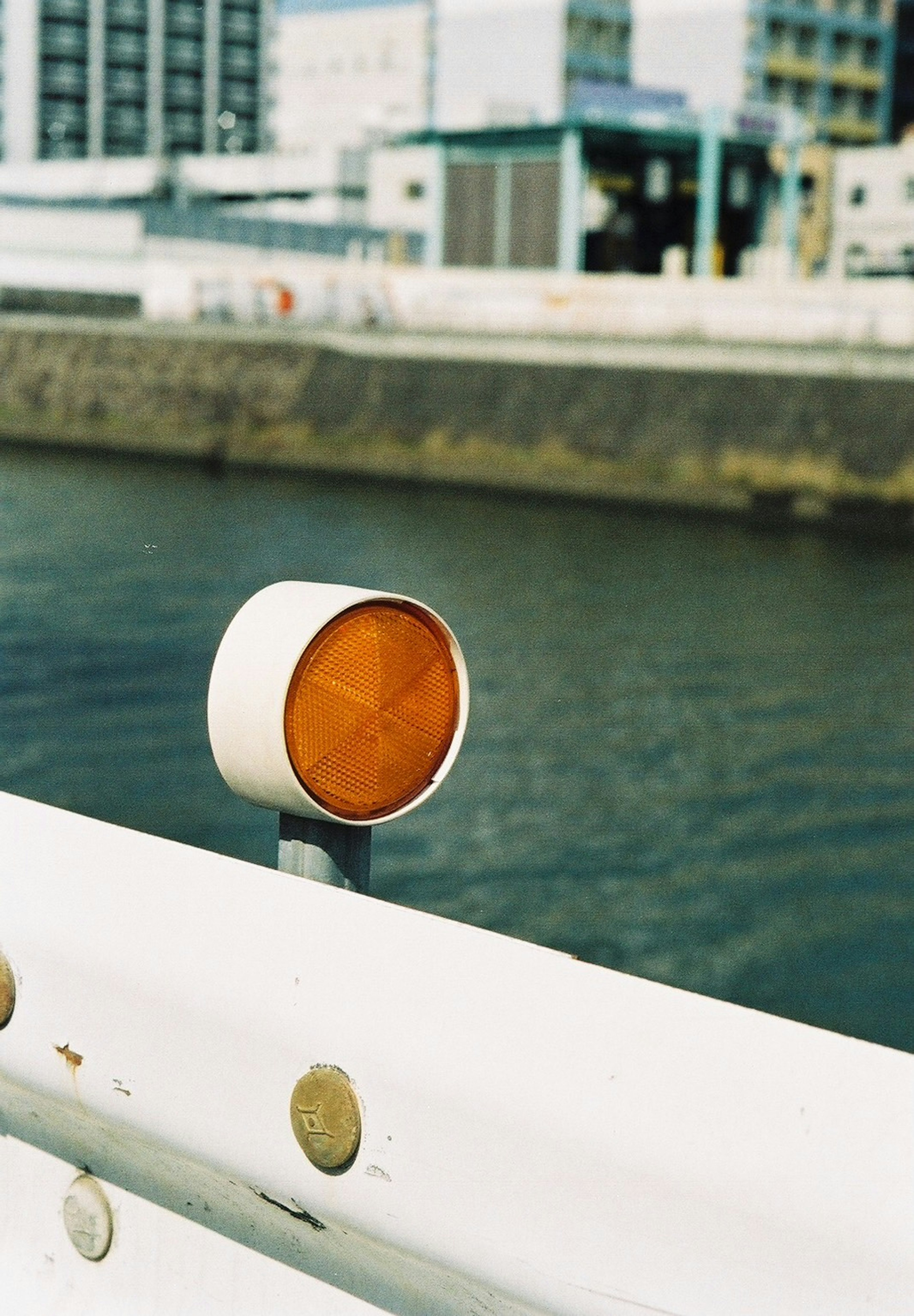 Orange circular sign mounted on white railing by the water