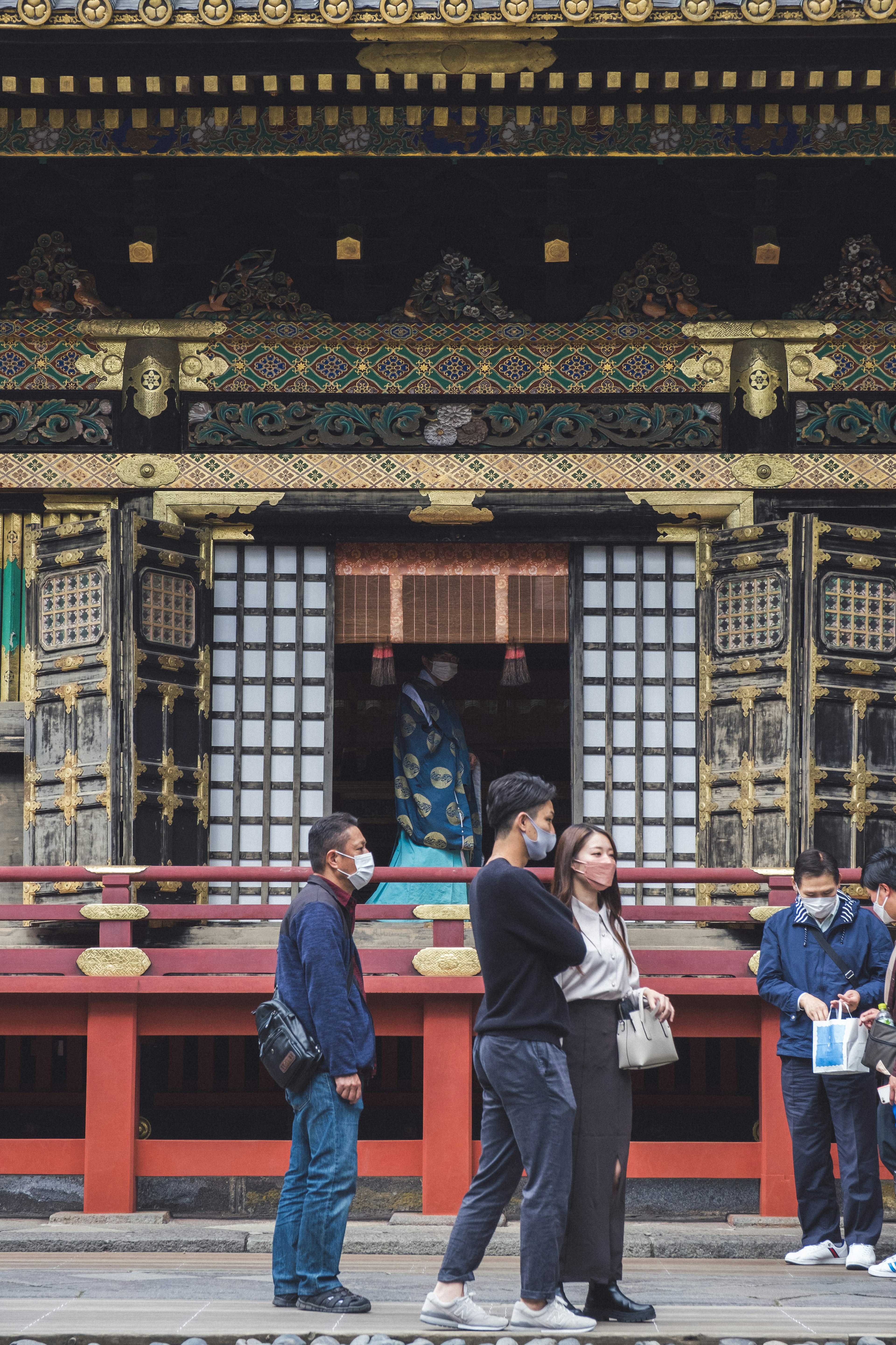 A group of visitors in front of a shrine building with intricate designs