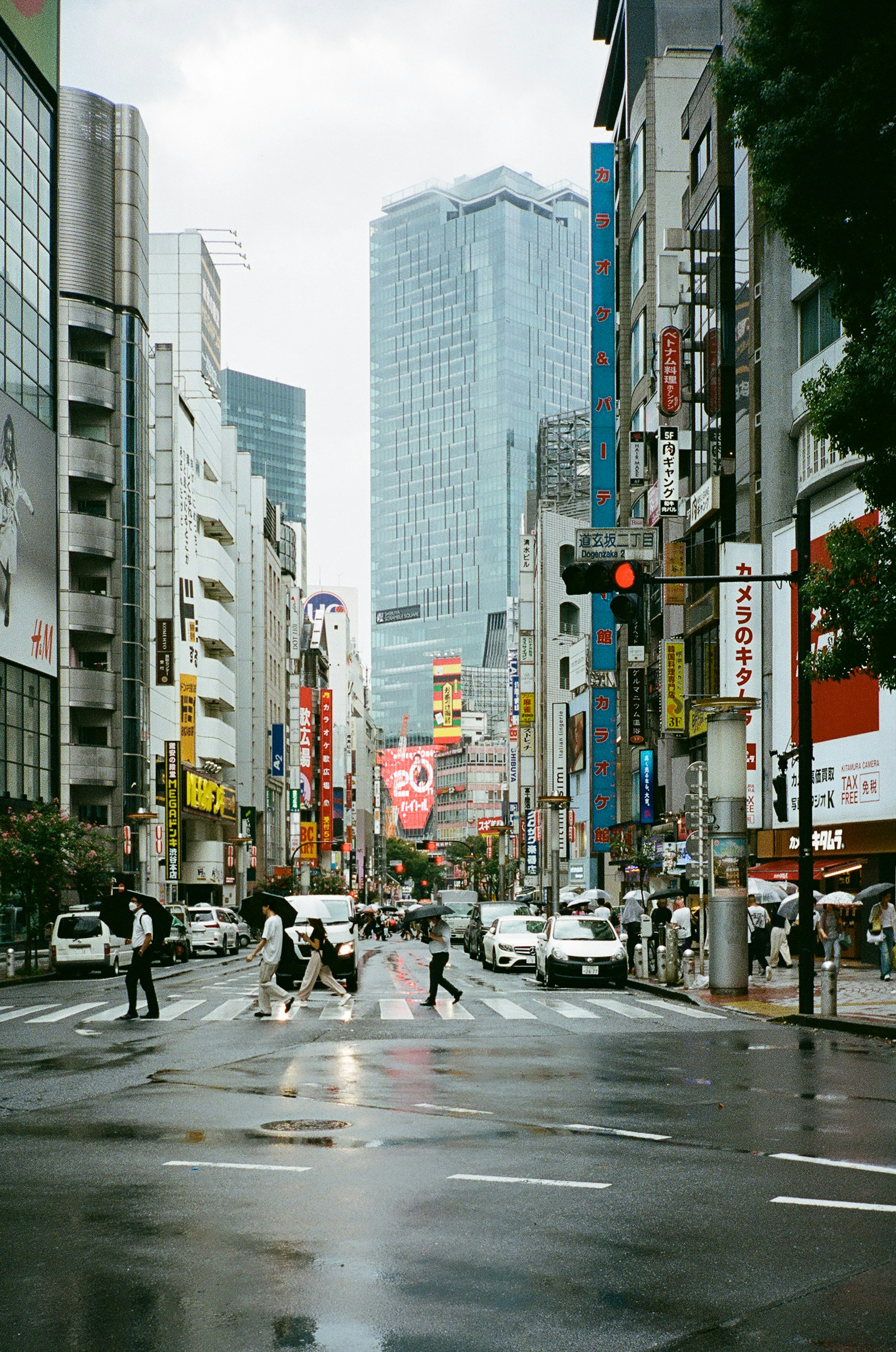 雨の中で交差点を渡る人々と高層ビルの風景