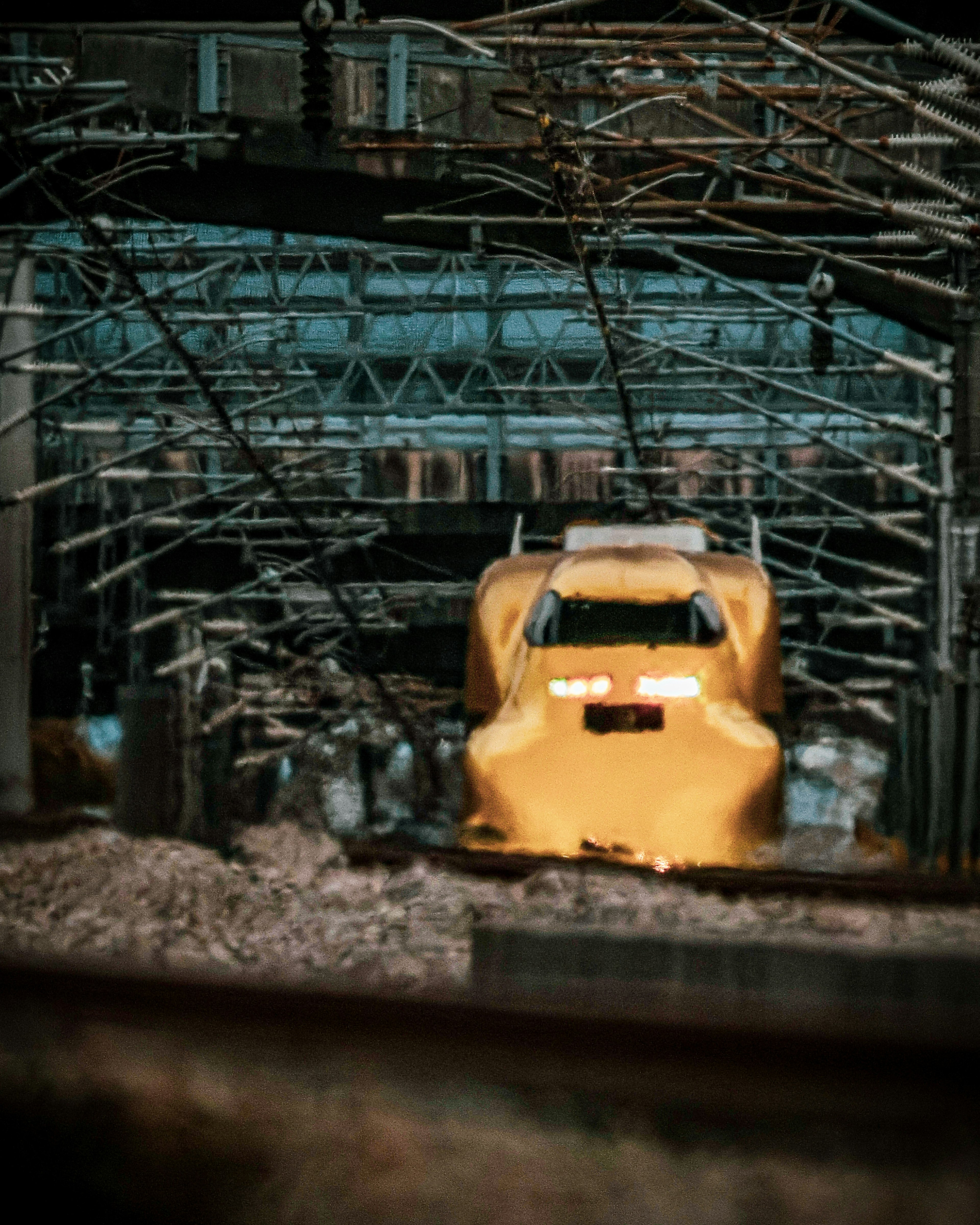 Shinkansen giallo visibile sotto strutture ferroviarie