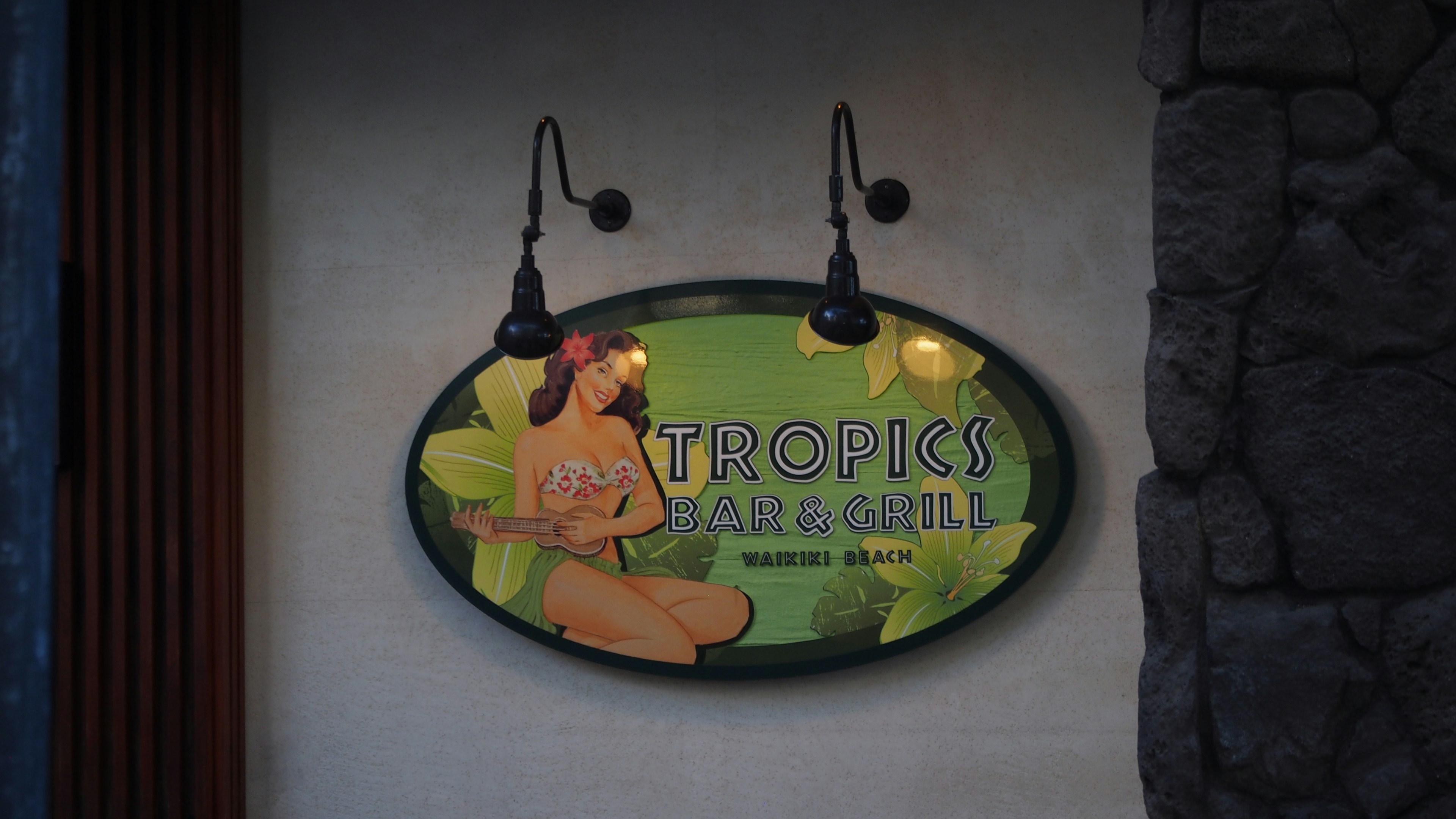 A sign featuring a tropical design with a woman in a colorful setting