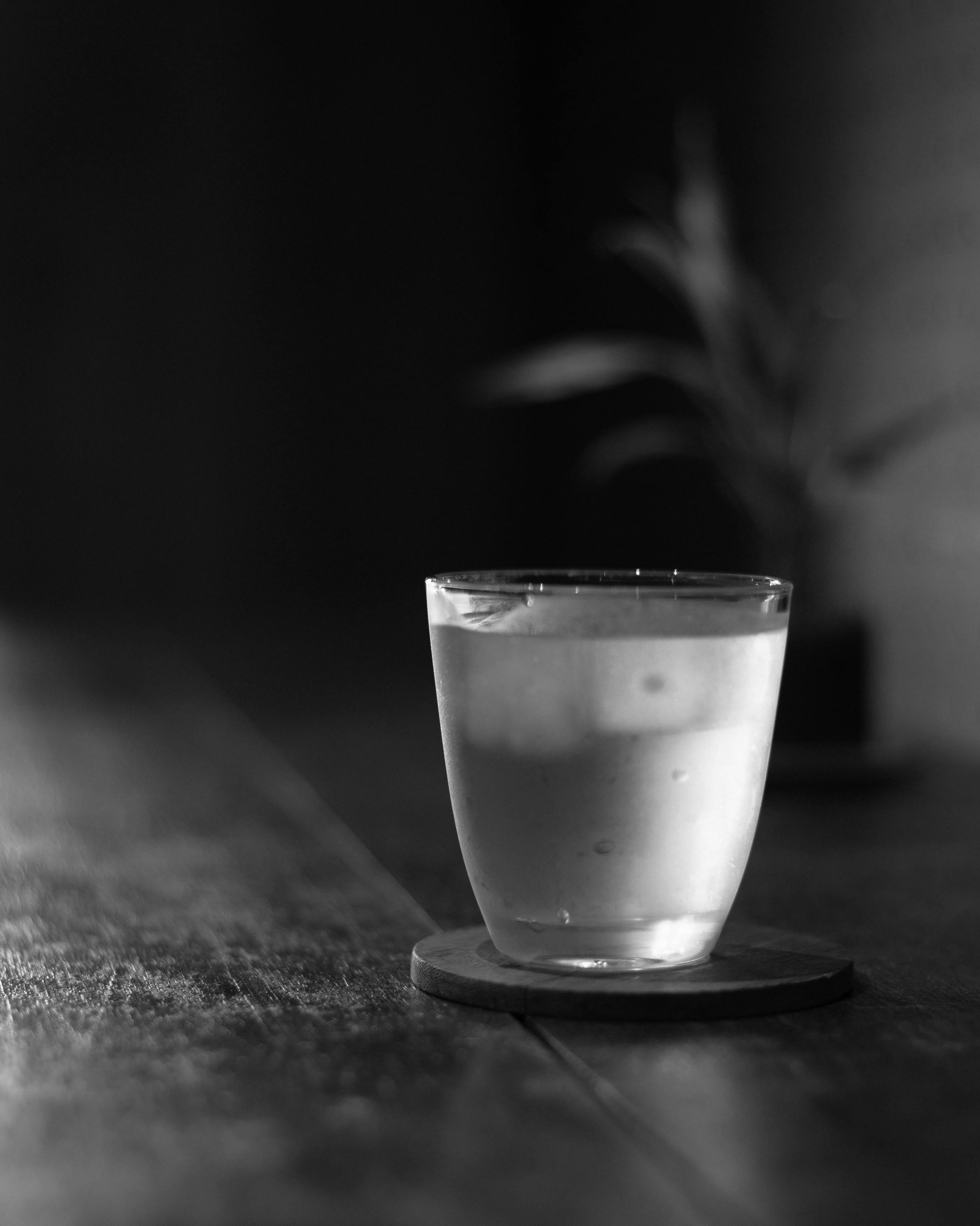 Une image en monochrome d'un verre transparent avec de l'eau glacée sur une surface en bois