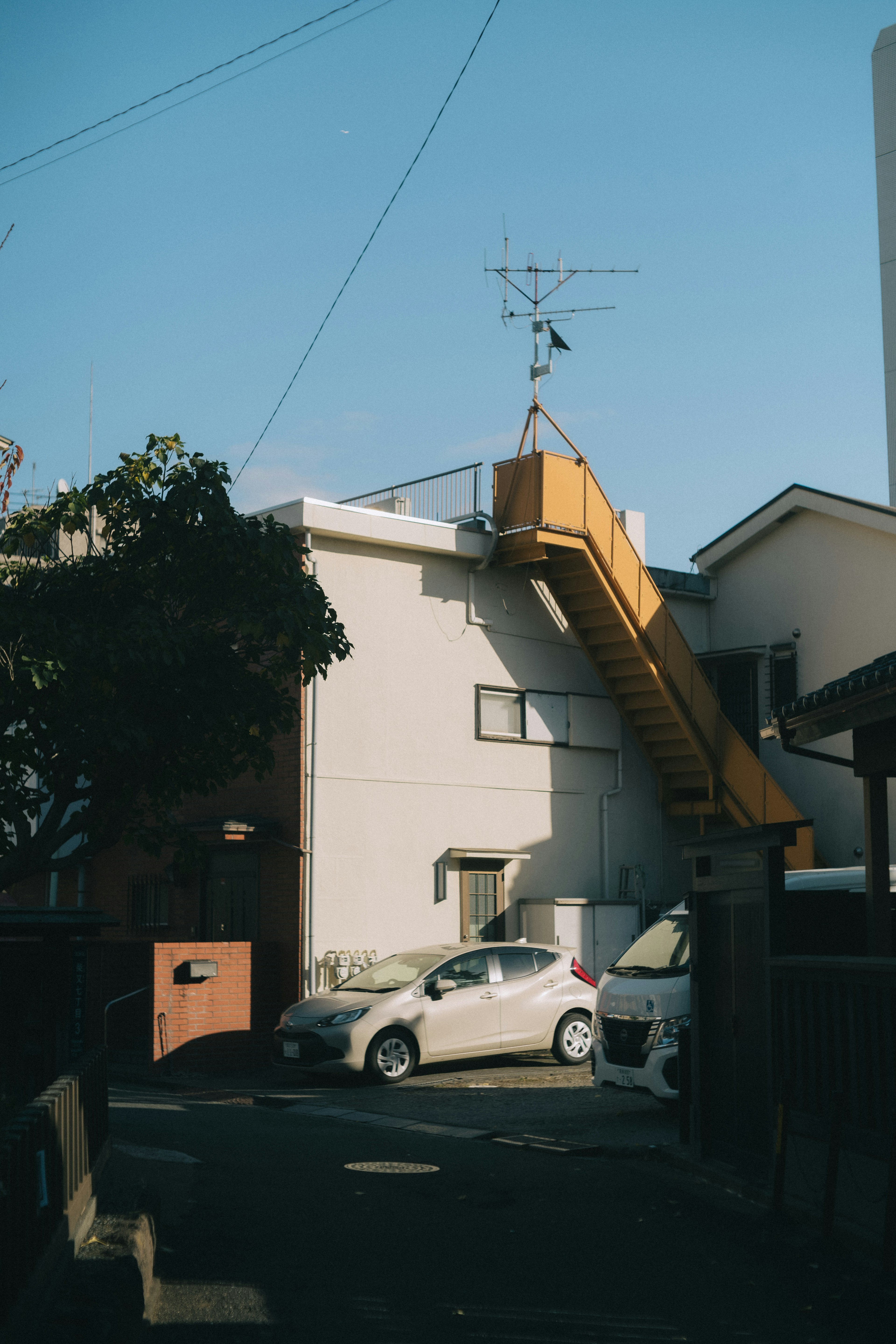 Extérieur d'un bâtiment blanc avec un escalier jaune et une voiture garée