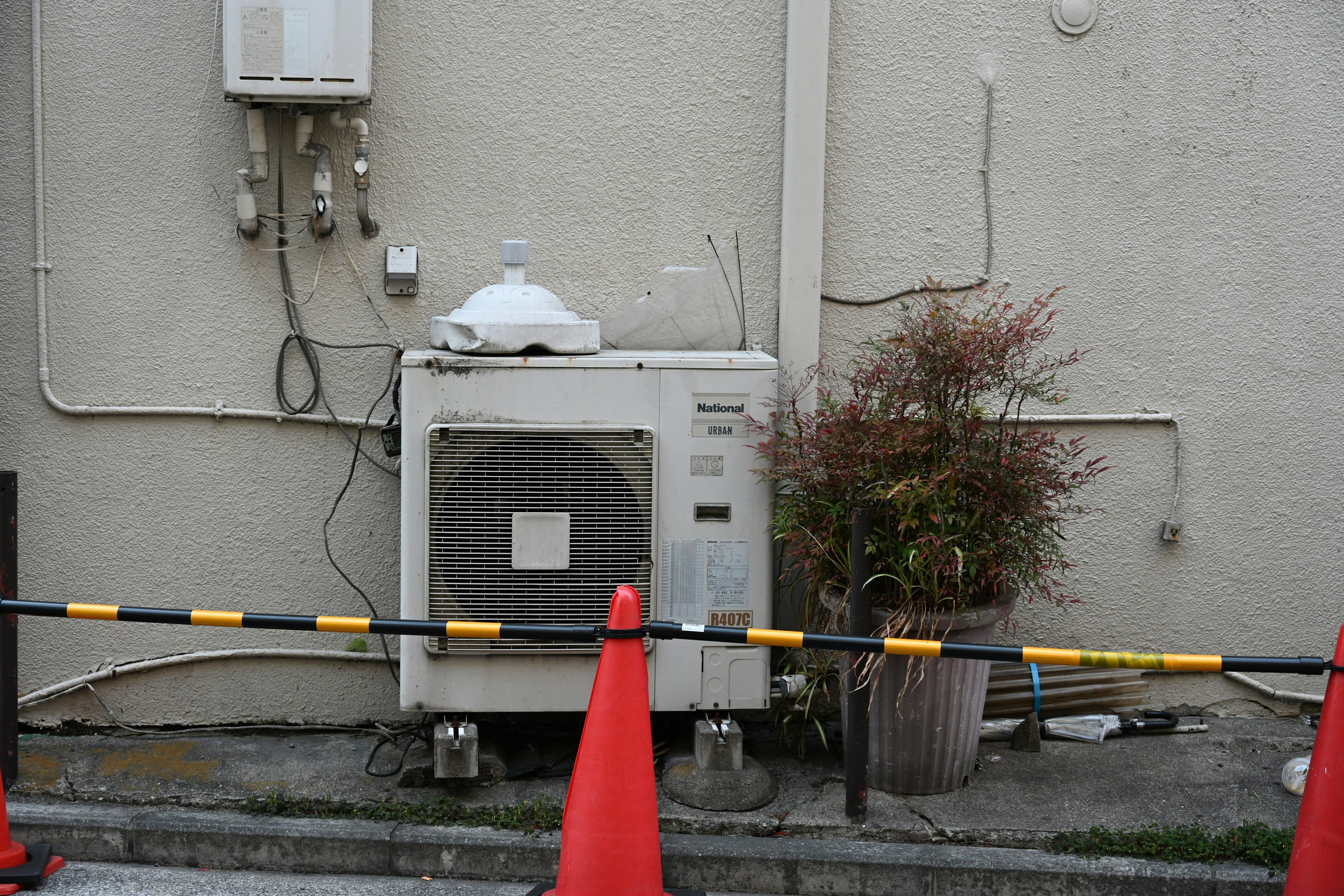 Air conditioning unit mounted on a wall with surrounding plants