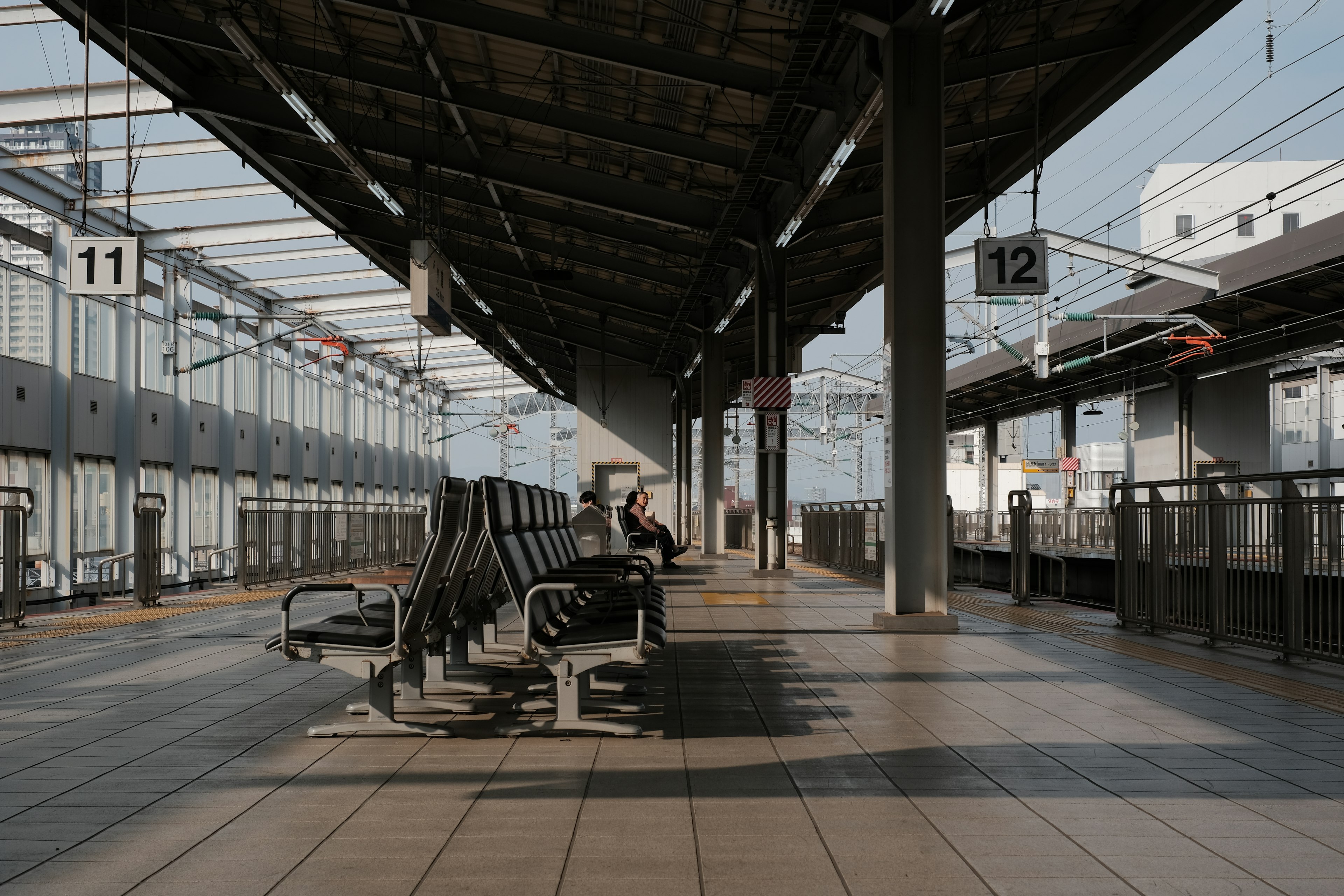 Plateforme de train calme avec une personne assise et des panneaux de départ de train