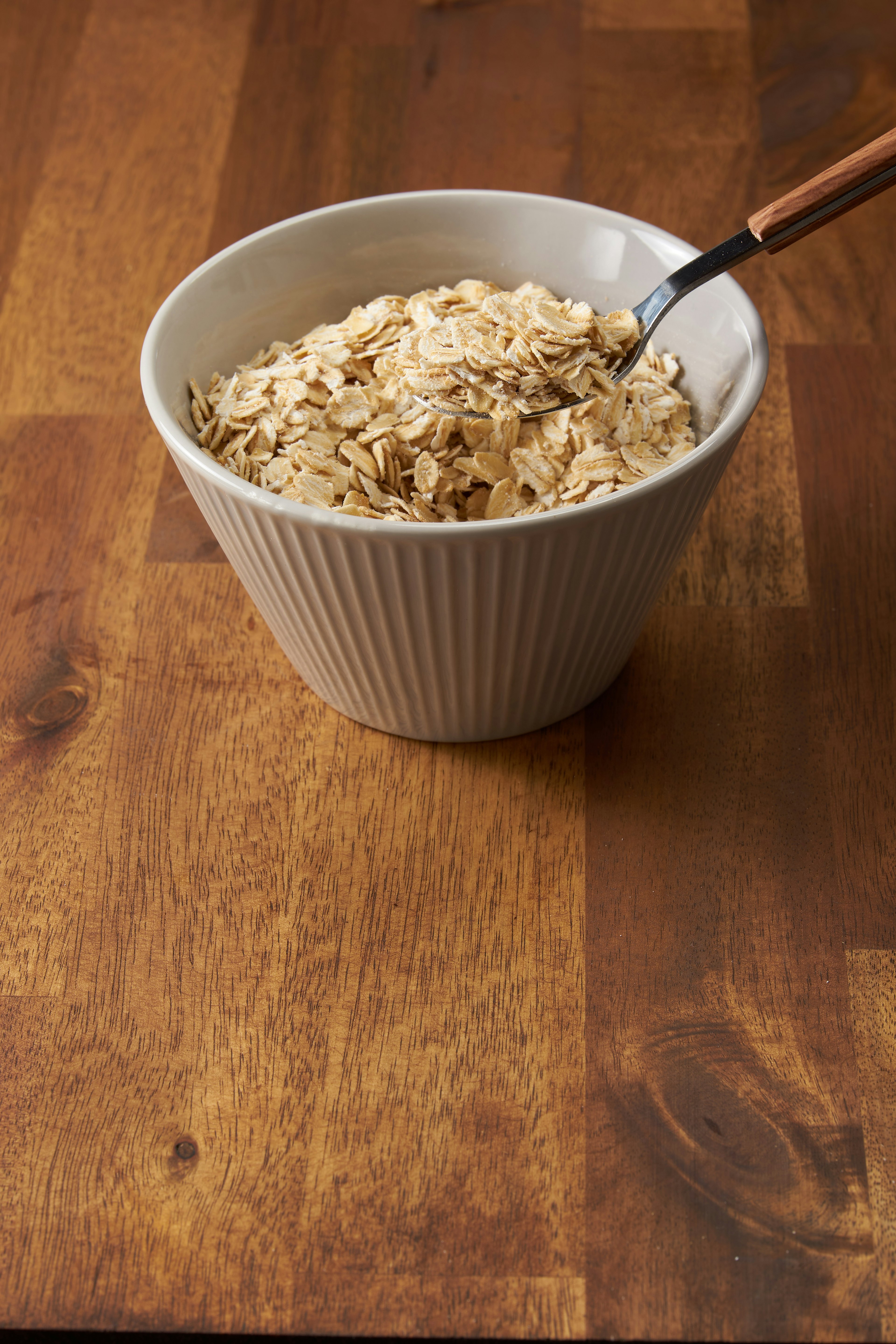 Schüssel mit Haferflocken auf einem Holztisch mit einem Löffel