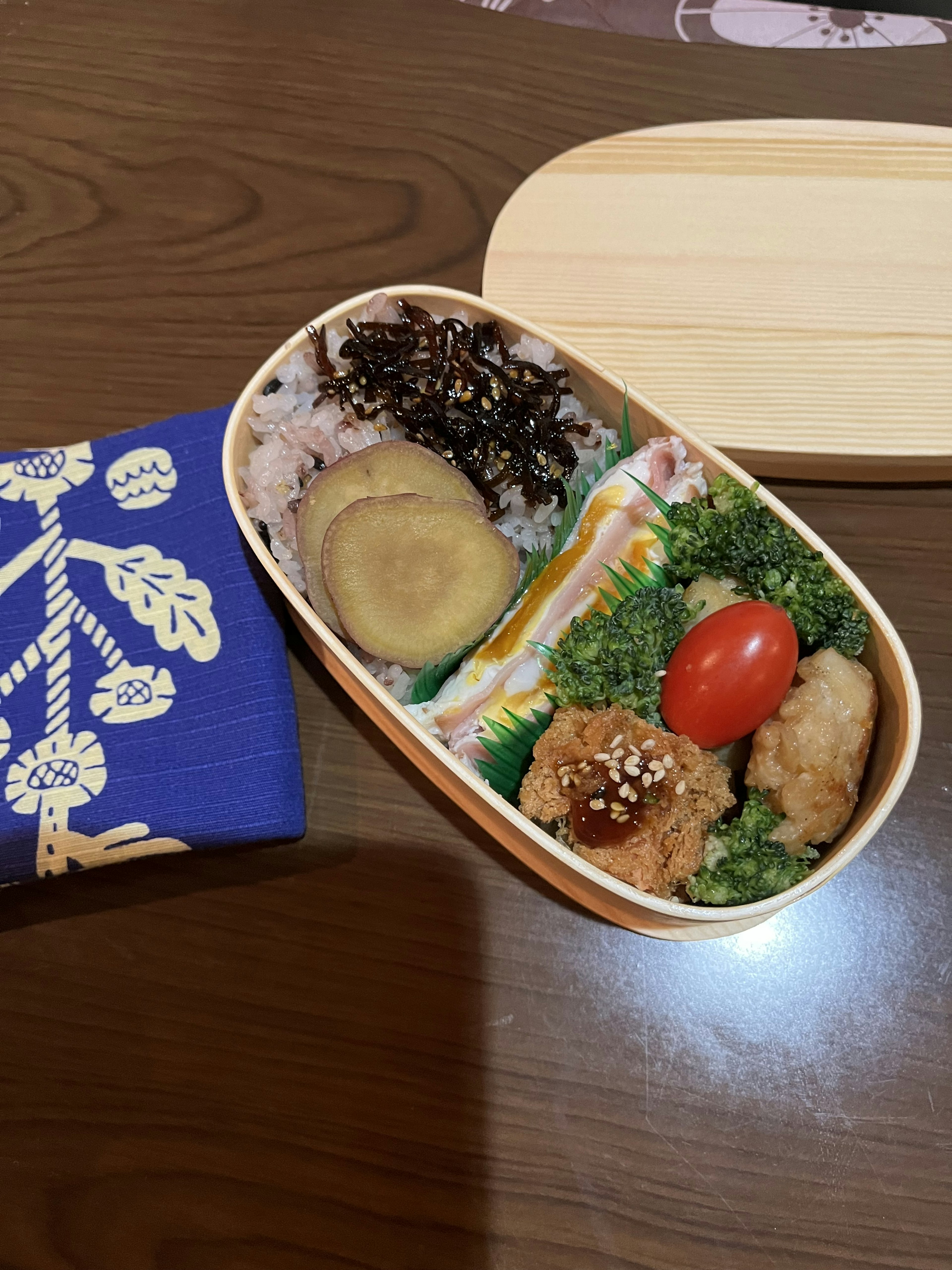 A colorful bento box filled with various dishes and a blue cloth