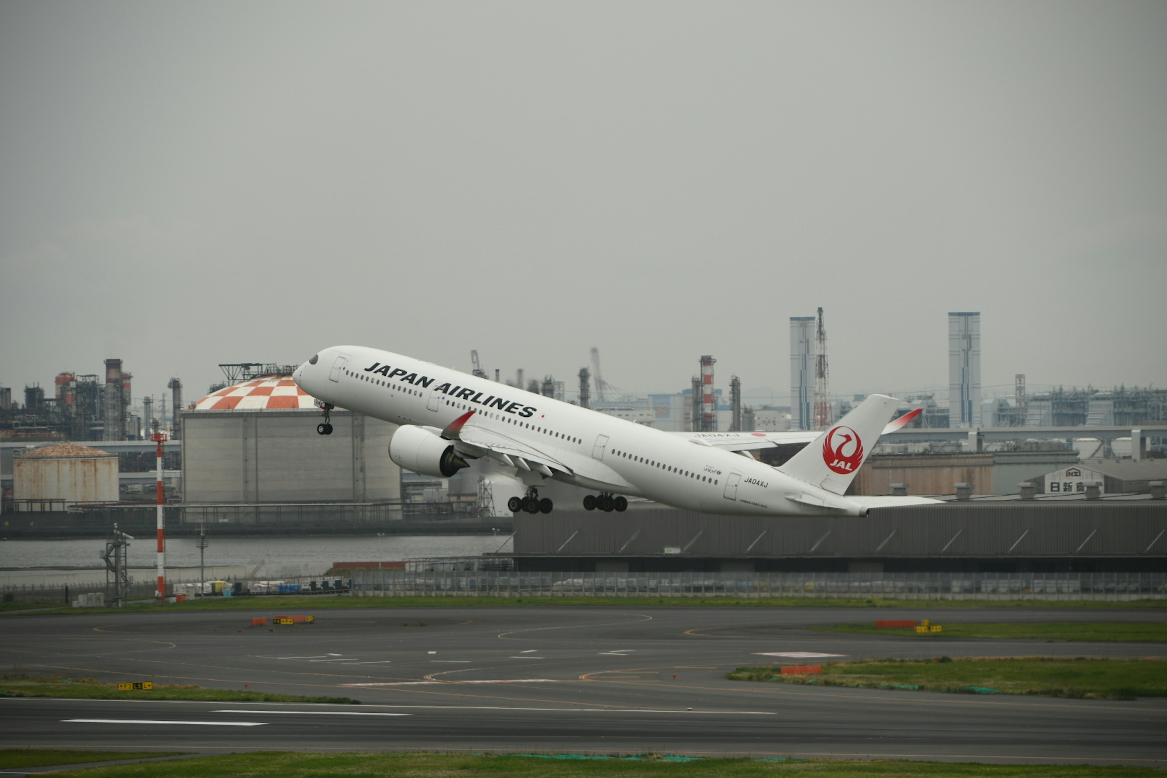 Pesawat penumpang Japan Airlines lepas landas di bawah langit mendung