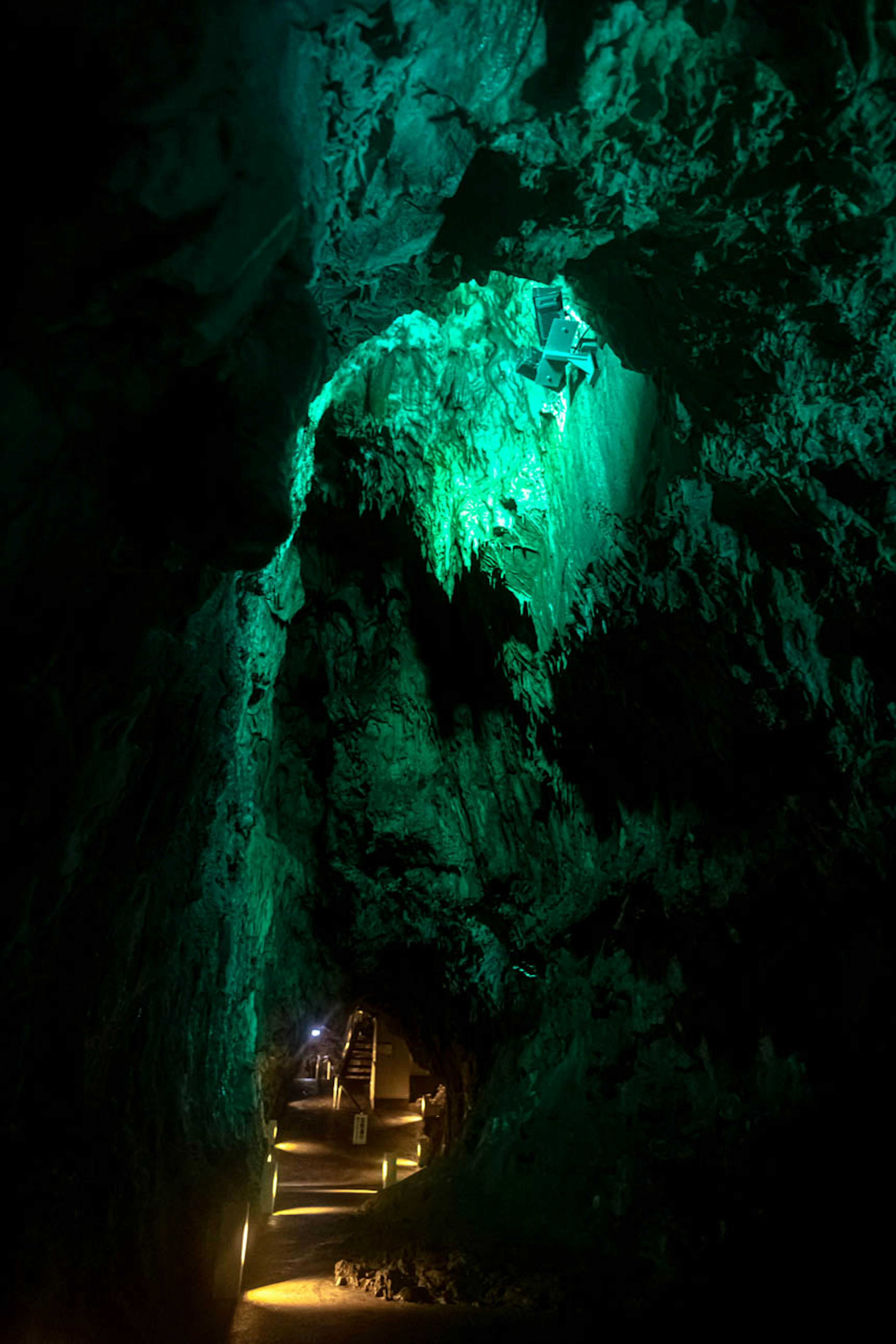 Interior de cueva iluminado con luz verde y paredes rocosas